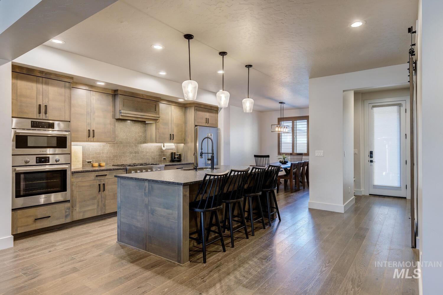 Kitchen with a breakfast bar area, decorative light fixtures, a center island with sink, backsplash, and recessed lighting