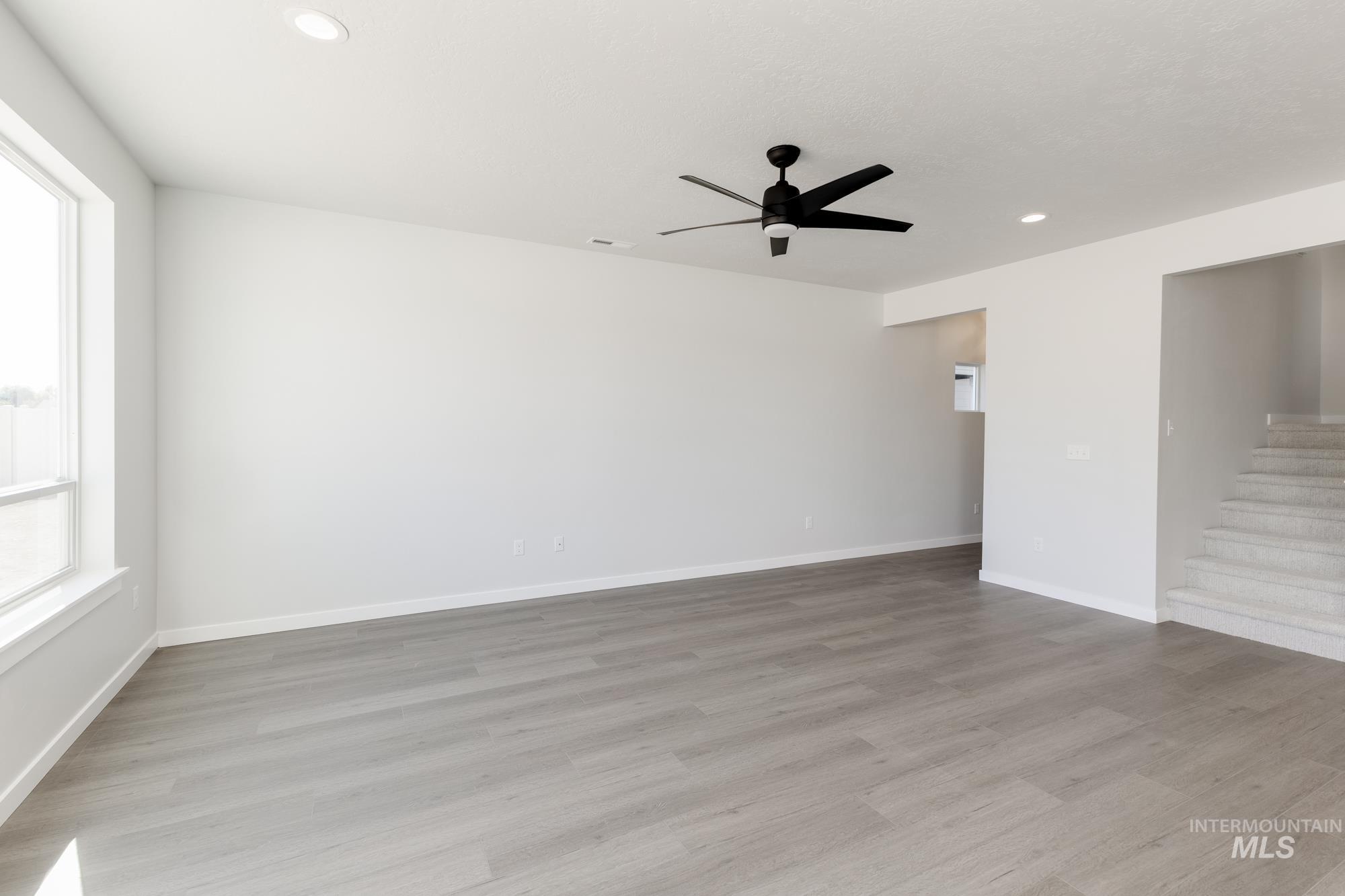 Empty room with light wood-style floors, recessed lighting, a ceiling fan, and stairway