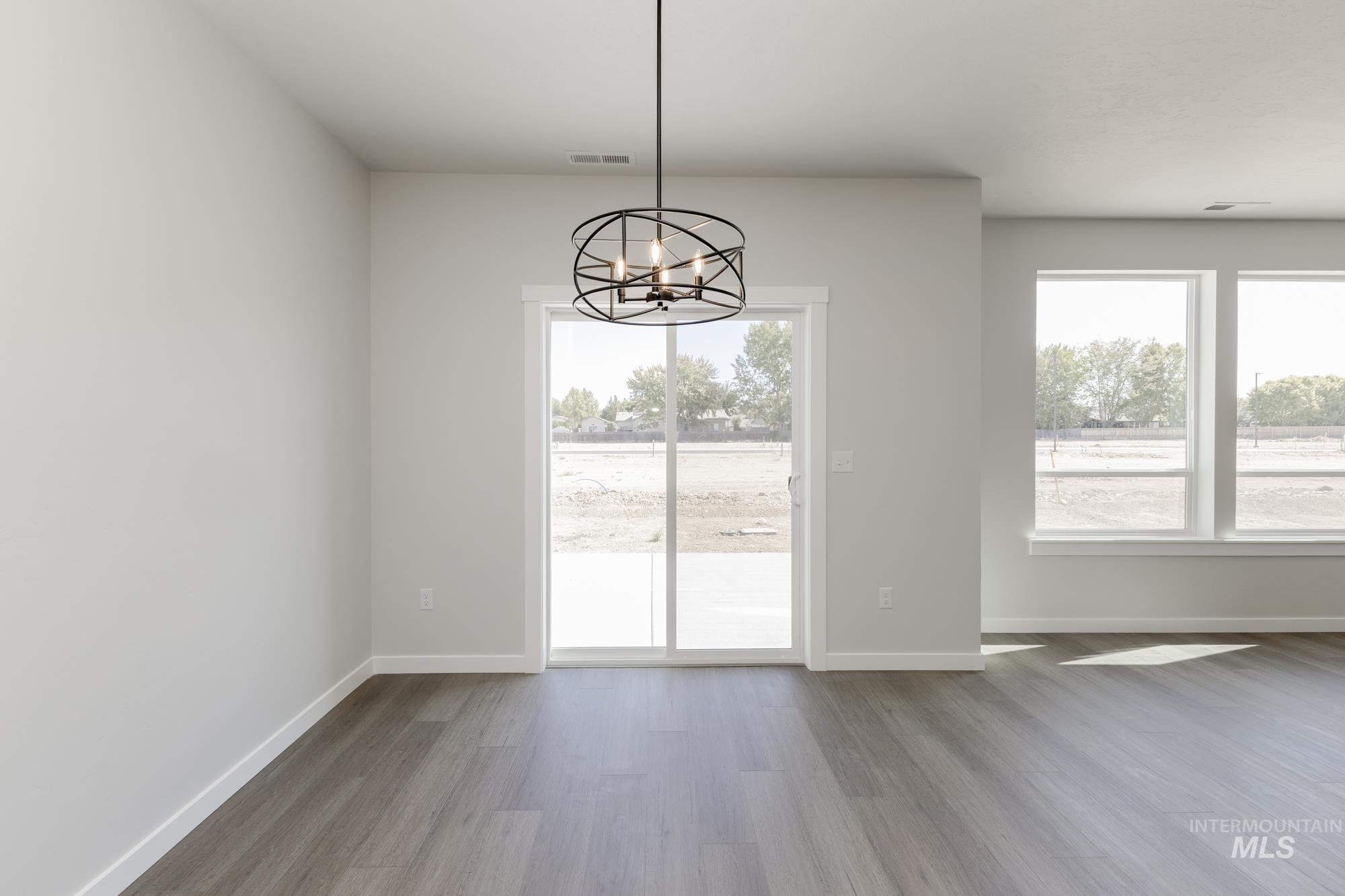 Unfurnished dining area with plenty of natural light, wood finished floors, and a chandelier