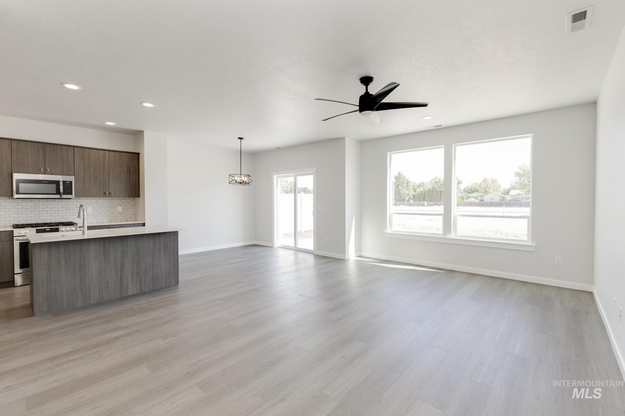 Unfurnished living room featuring light wood-type flooring, a ceiling fan, recessed lighting, and a chandelier