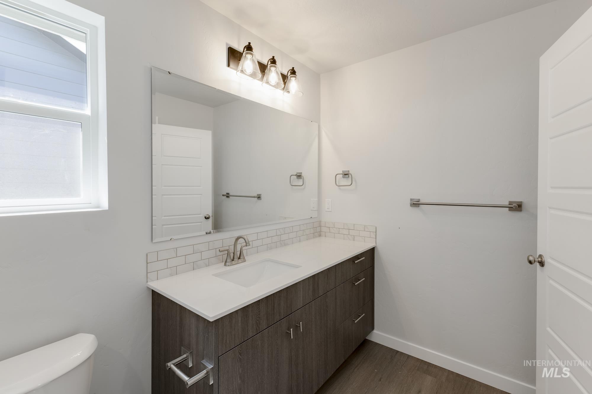 Half bathroom featuring vanity, dark wood-style flooring, and backsplash