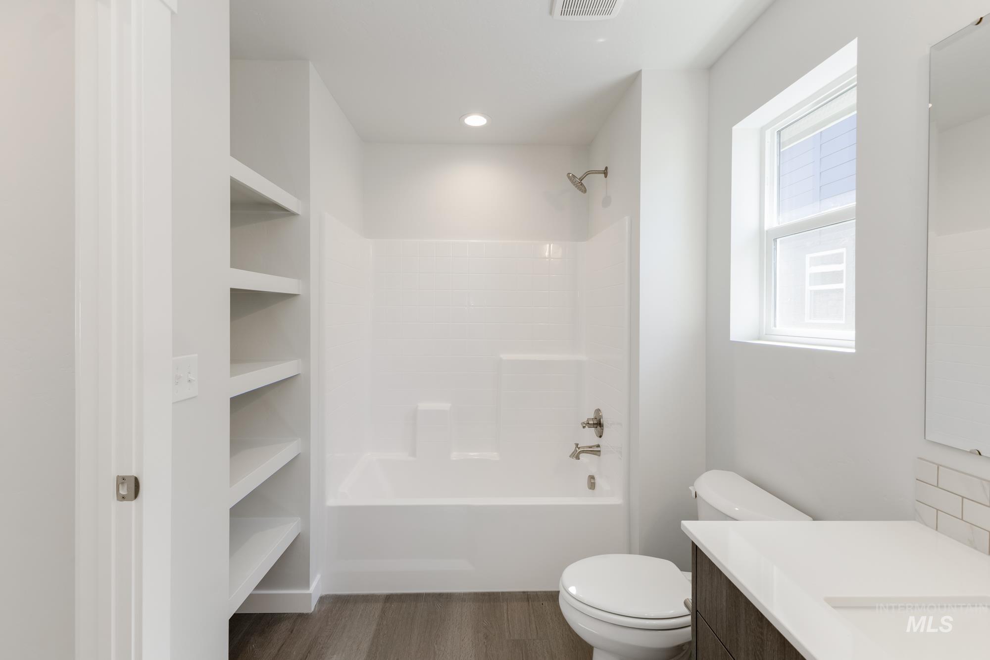 Bathroom with shower / bathtub combination, vanity, and dark wood-style floors