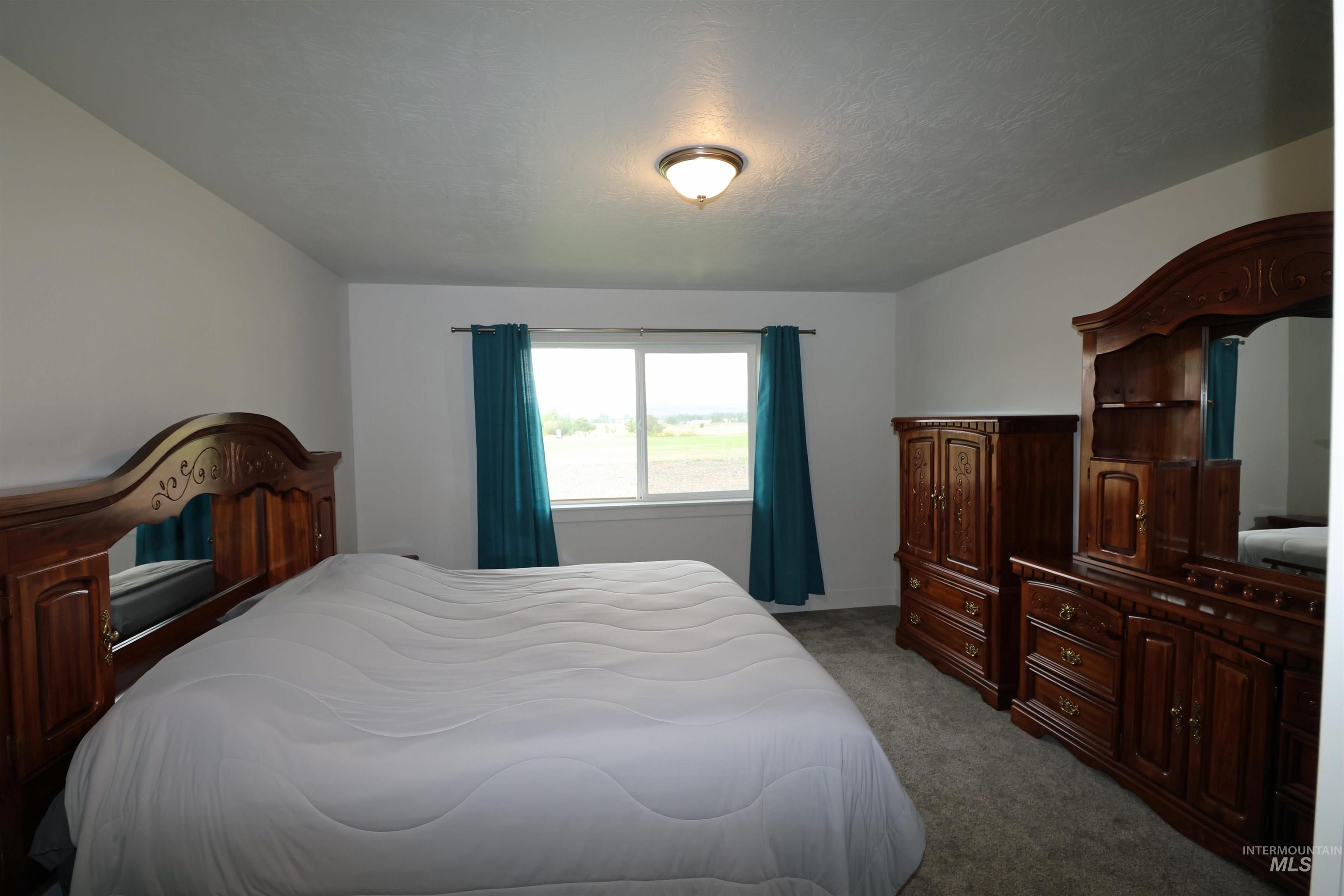 Carpeted bedroom featuring a textured ceiling and baseboards