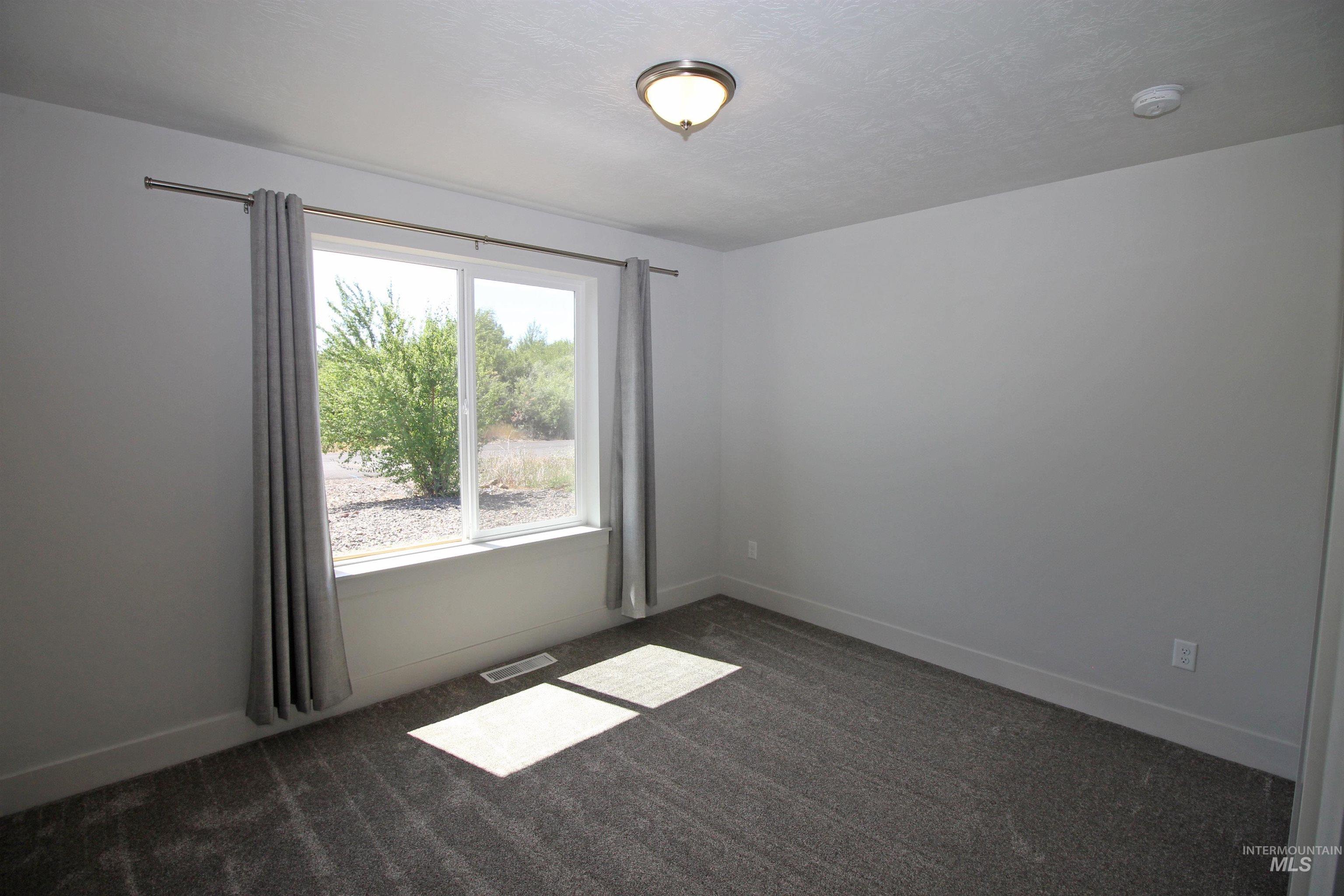 Unfurnished room featuring dark colored carpet and a textured ceiling