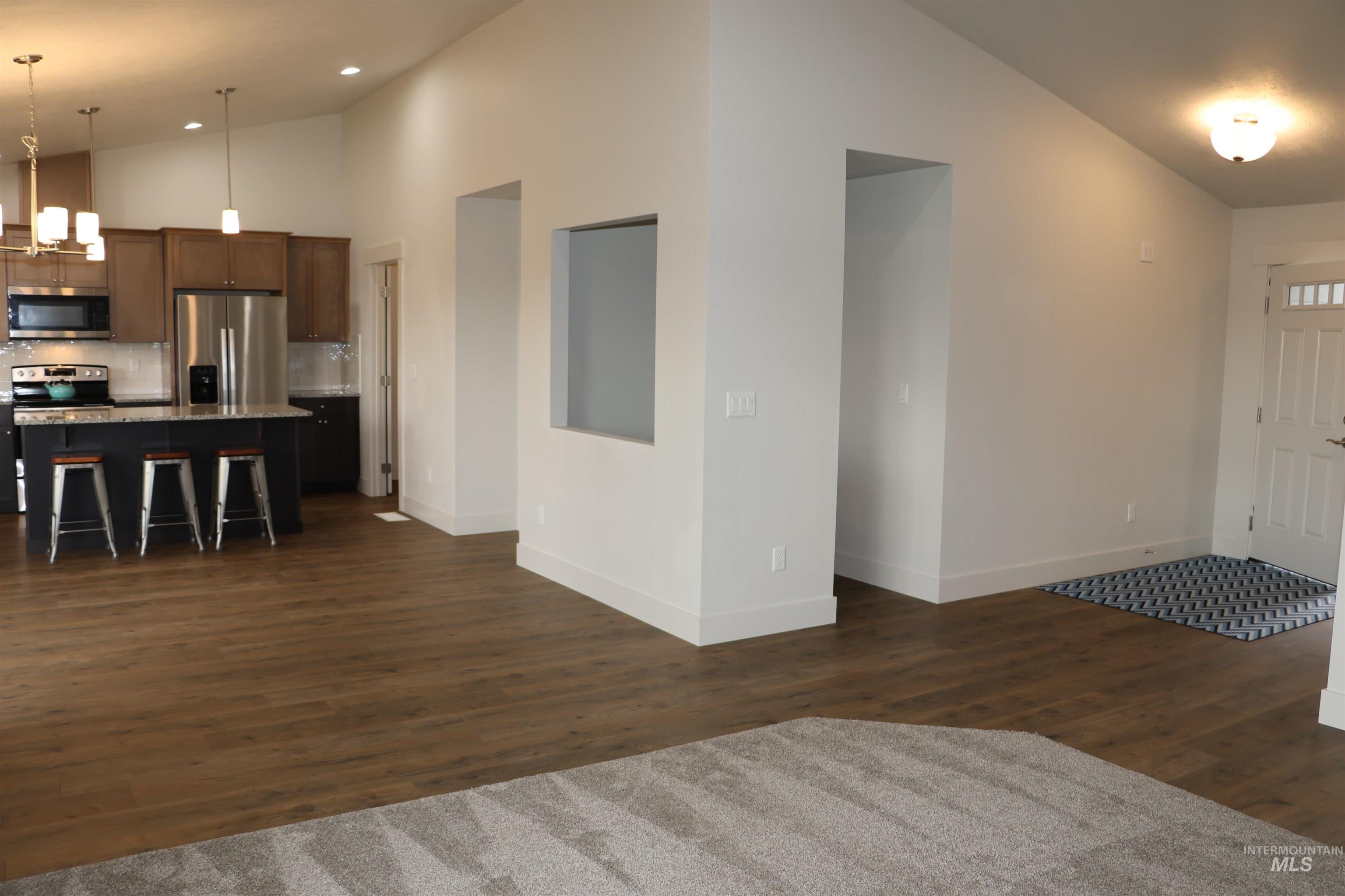 Entrance foyer featuring dark wood-style floors, high vaulted ceiling, and recessed lighting