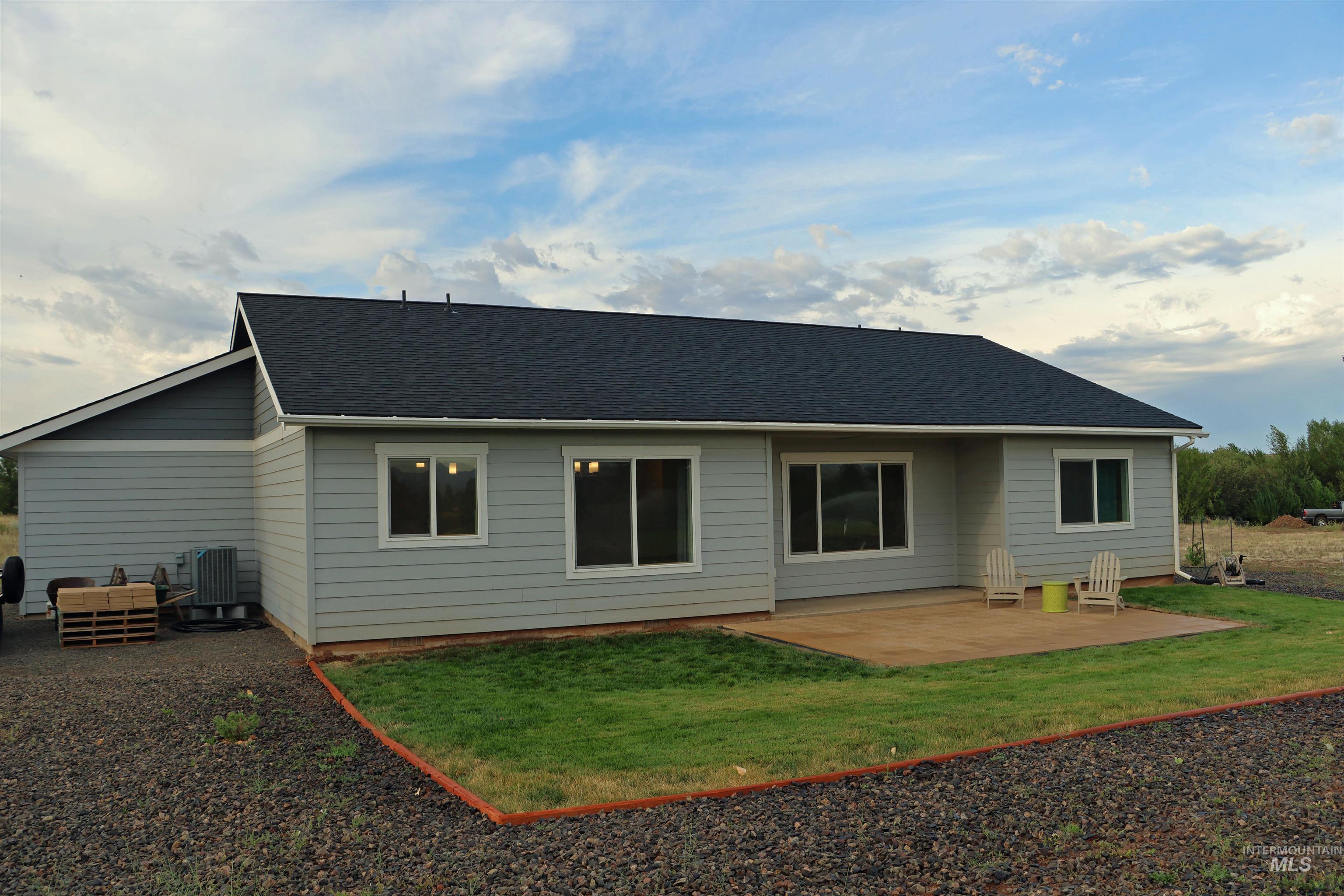 Rear view of property with a patio area, a yard, and a shingled roof