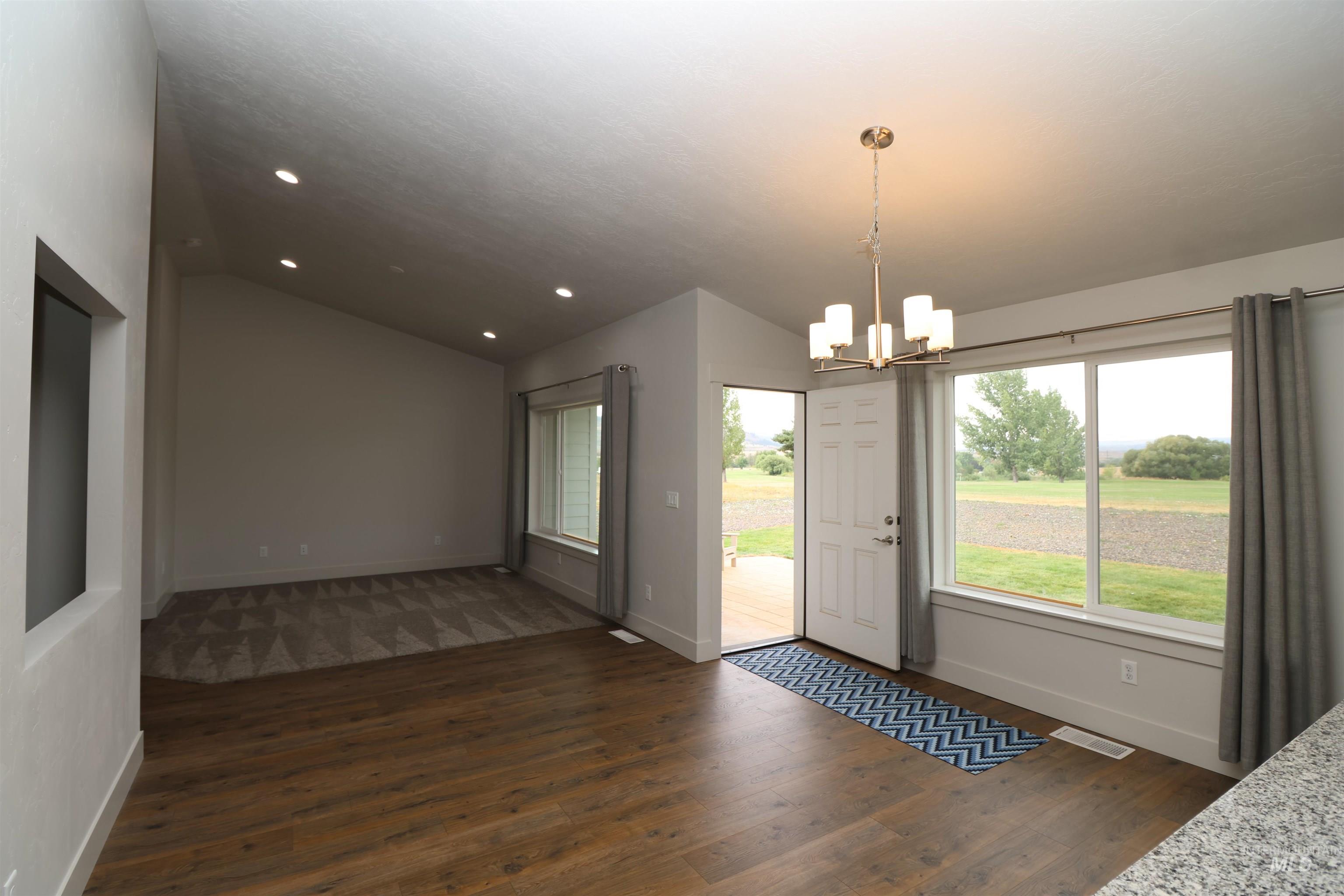 Doorway to outside featuring vaulted ceiling, a chandelier, dark wood-style floors, and recessed lighting