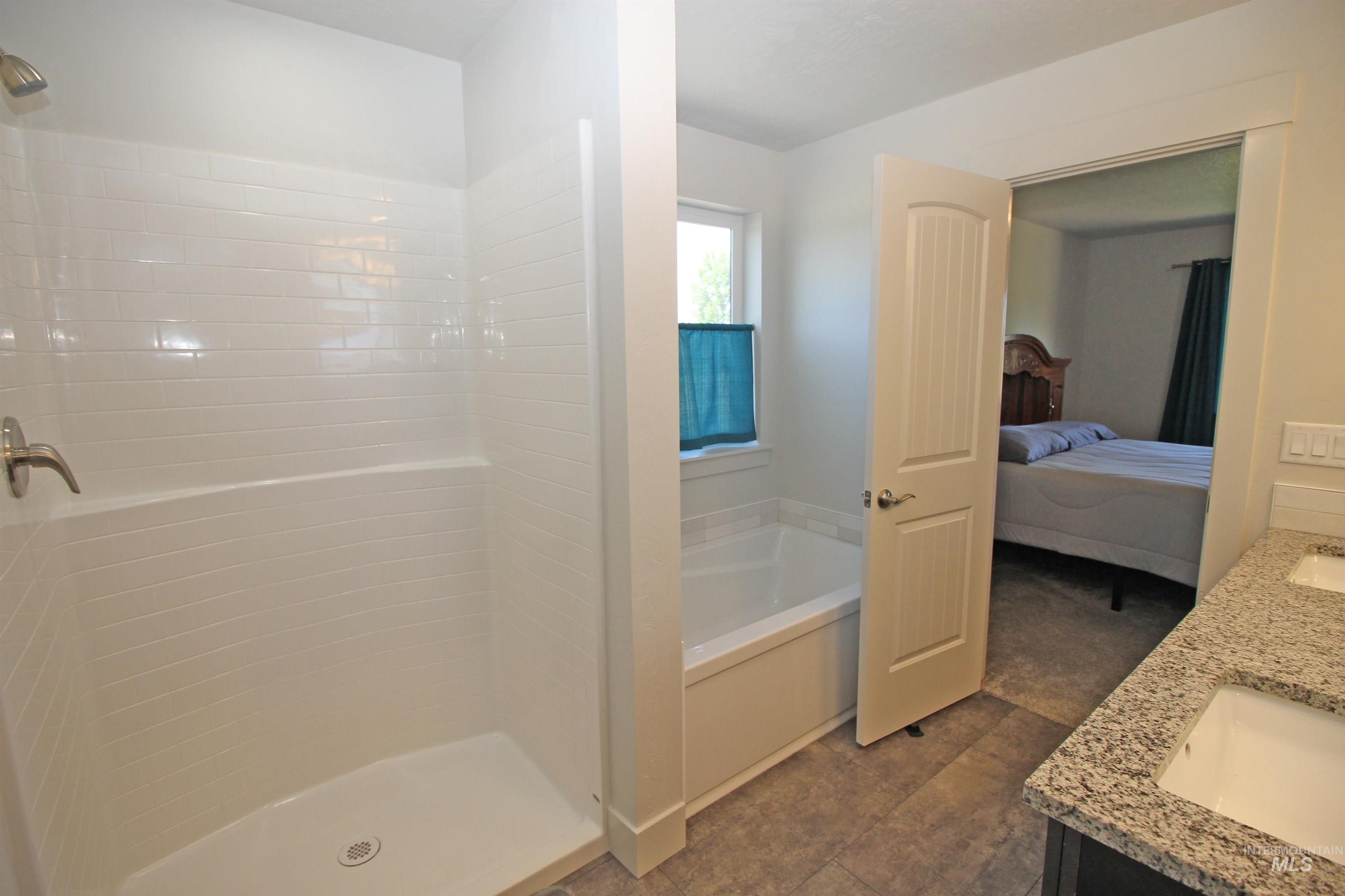 Ensuite bathroom featuring double vanity, a garden tub, and walk in shower
