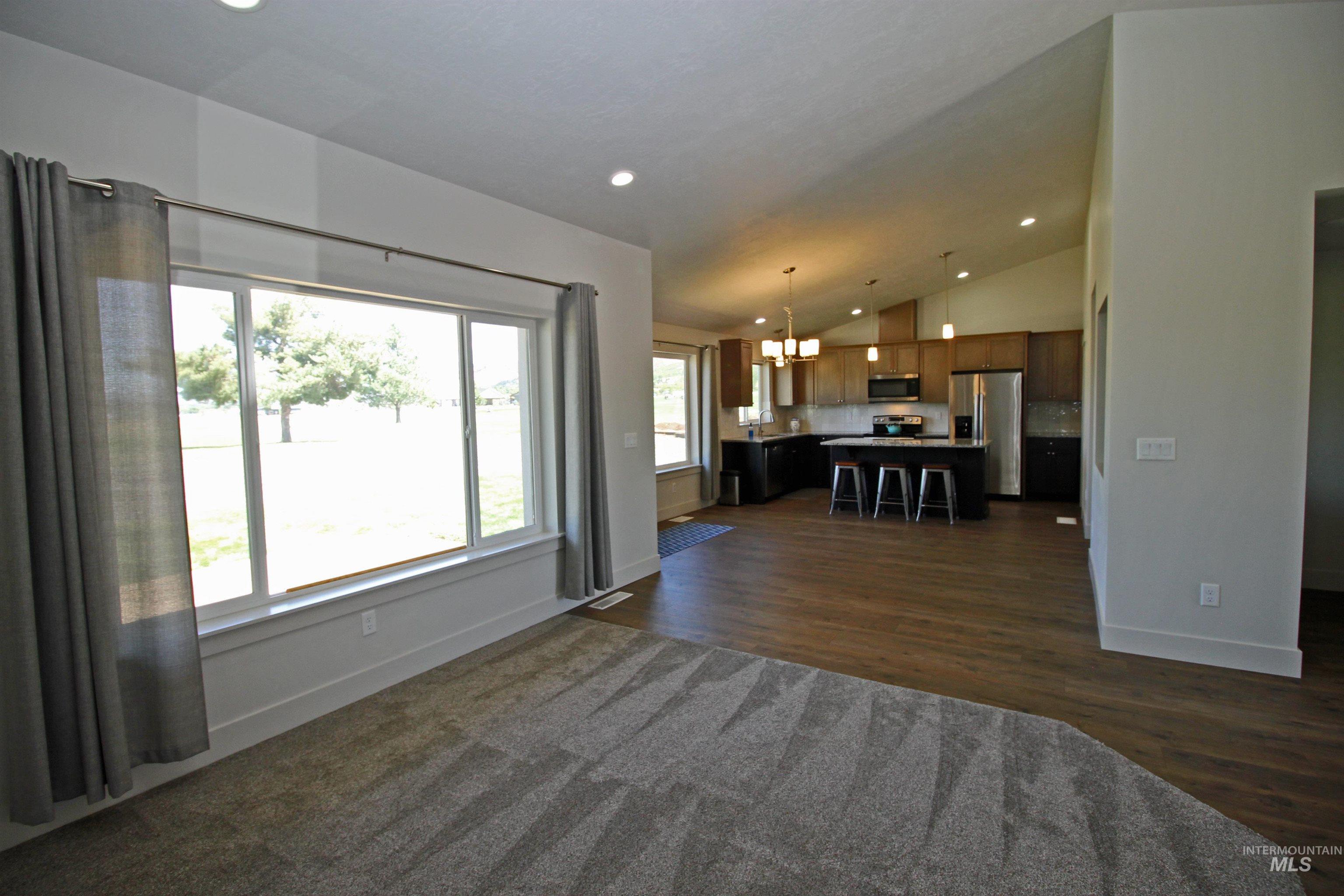 Living area featuring vaulted ceiling, a chandelier, recessed lighting, and dark wood finished floors