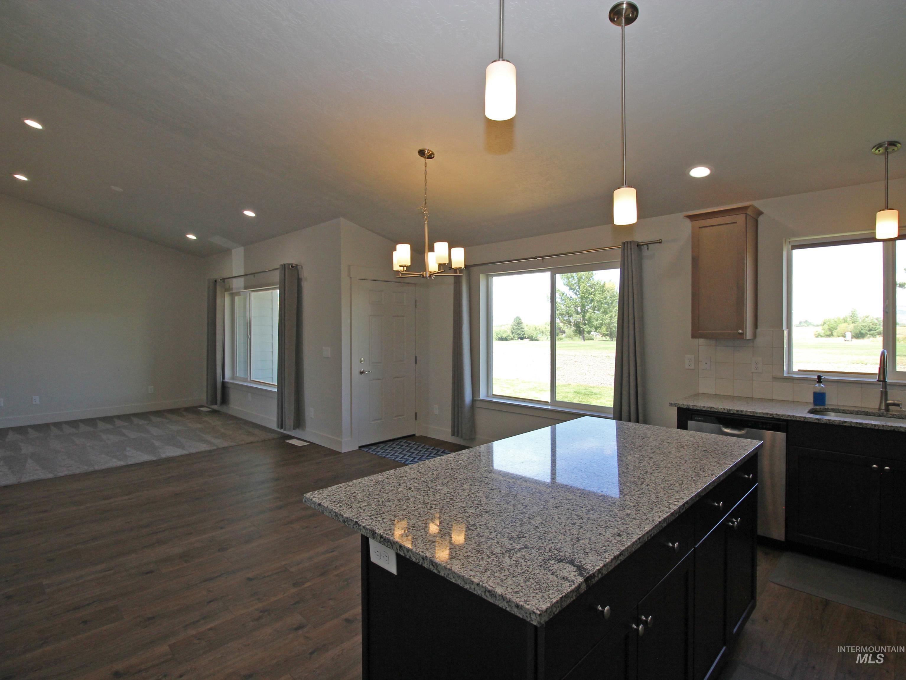 Kitchen featuring lofted ceiling, open floor plan, dark wood-style flooring, a center island, and recessed lighting