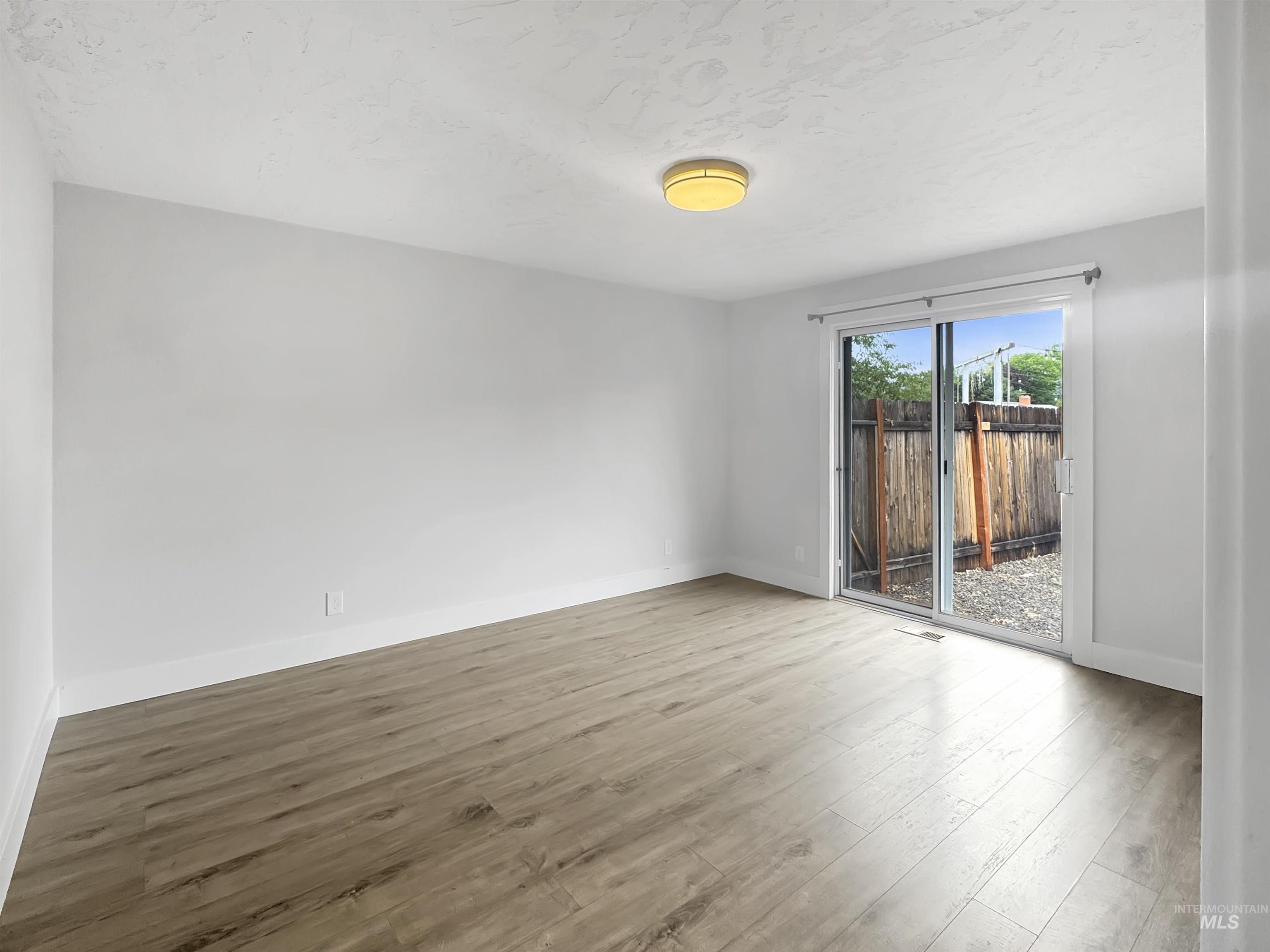 Room with wood-finish flooring, white walls, and a recessed ceiling light