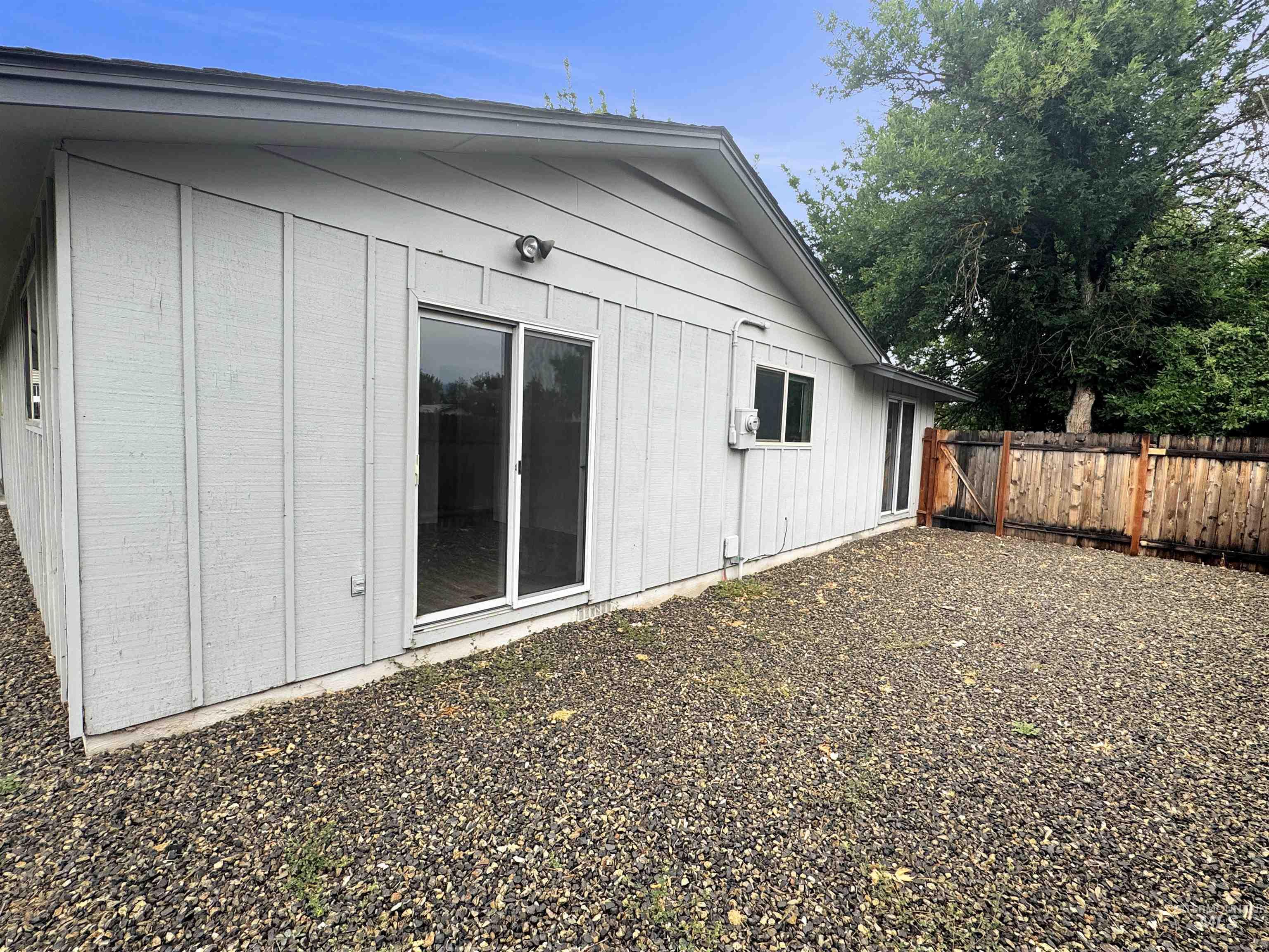 Exterior featuring vertical siding, a sliding glass door, and a privacy fence