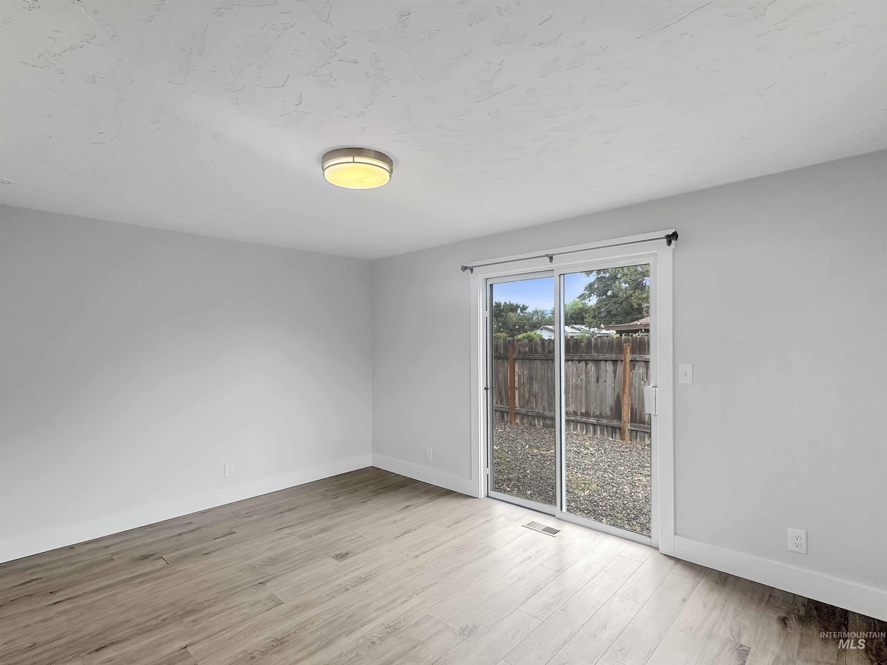 Room featuring light-toned wood-finish flooring, white walls, and a contemporary flush-mount ceiling light
