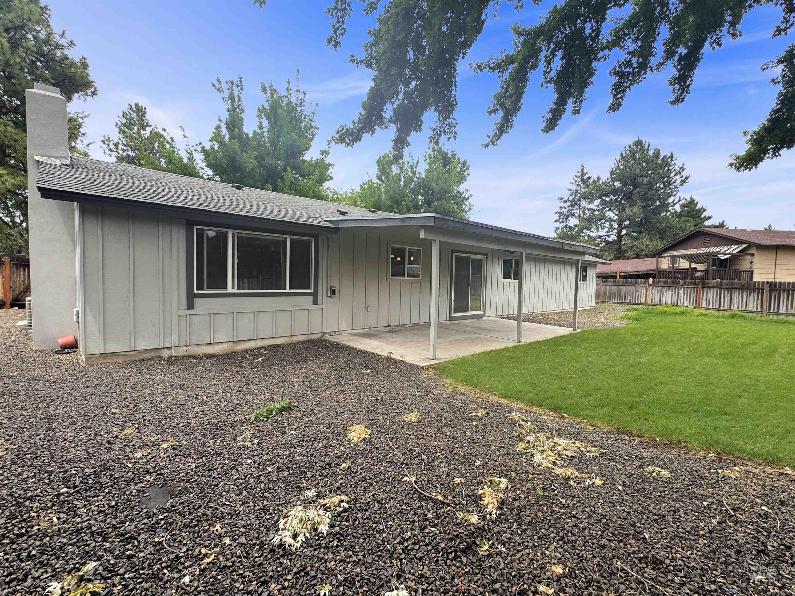 Rear exterior featuring a covered concrete patio, sliding glass door access, and a spacious lawn area
