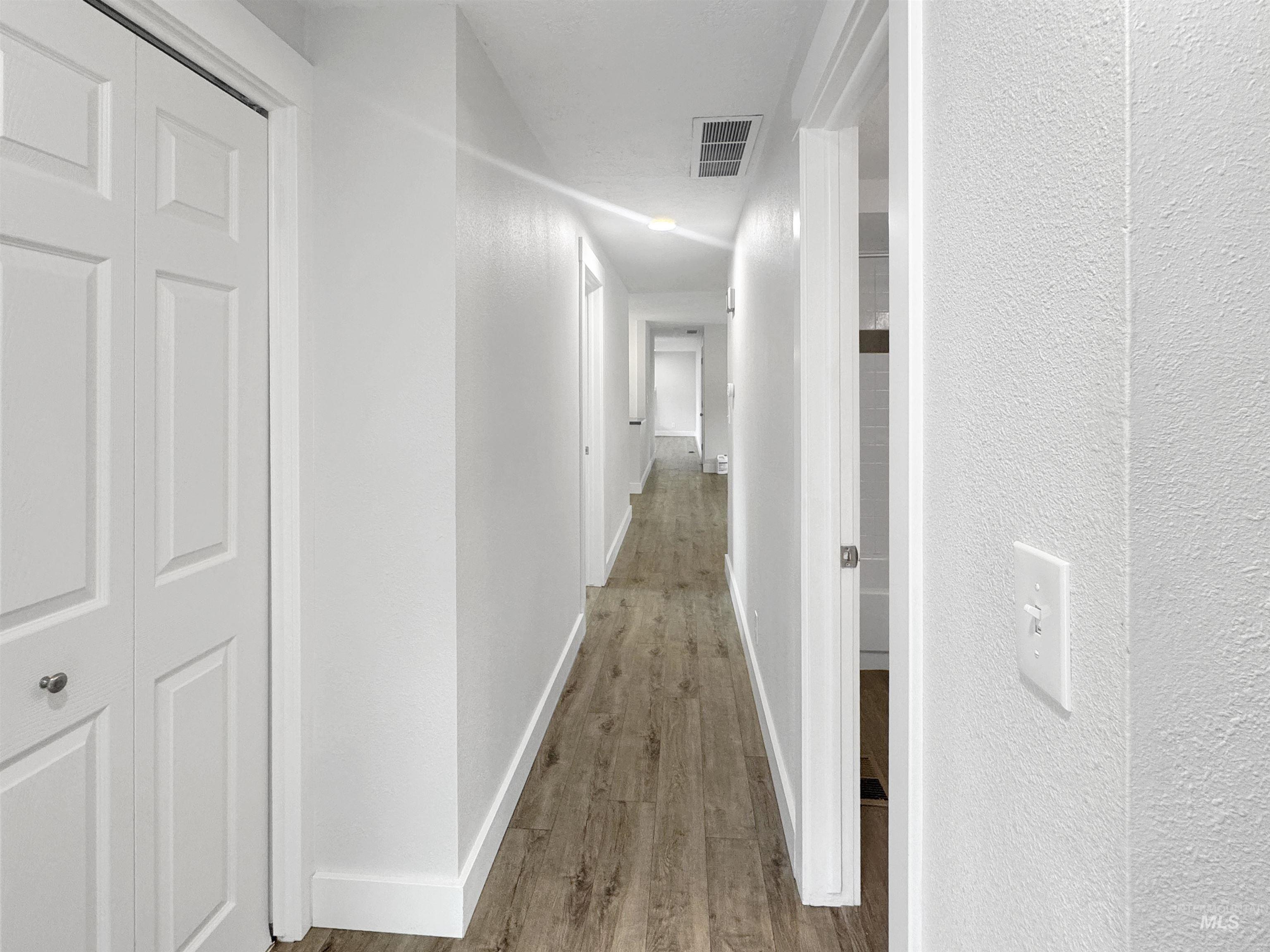 Hallway featuring wood-finish flooring, white walls, and recessed lighting