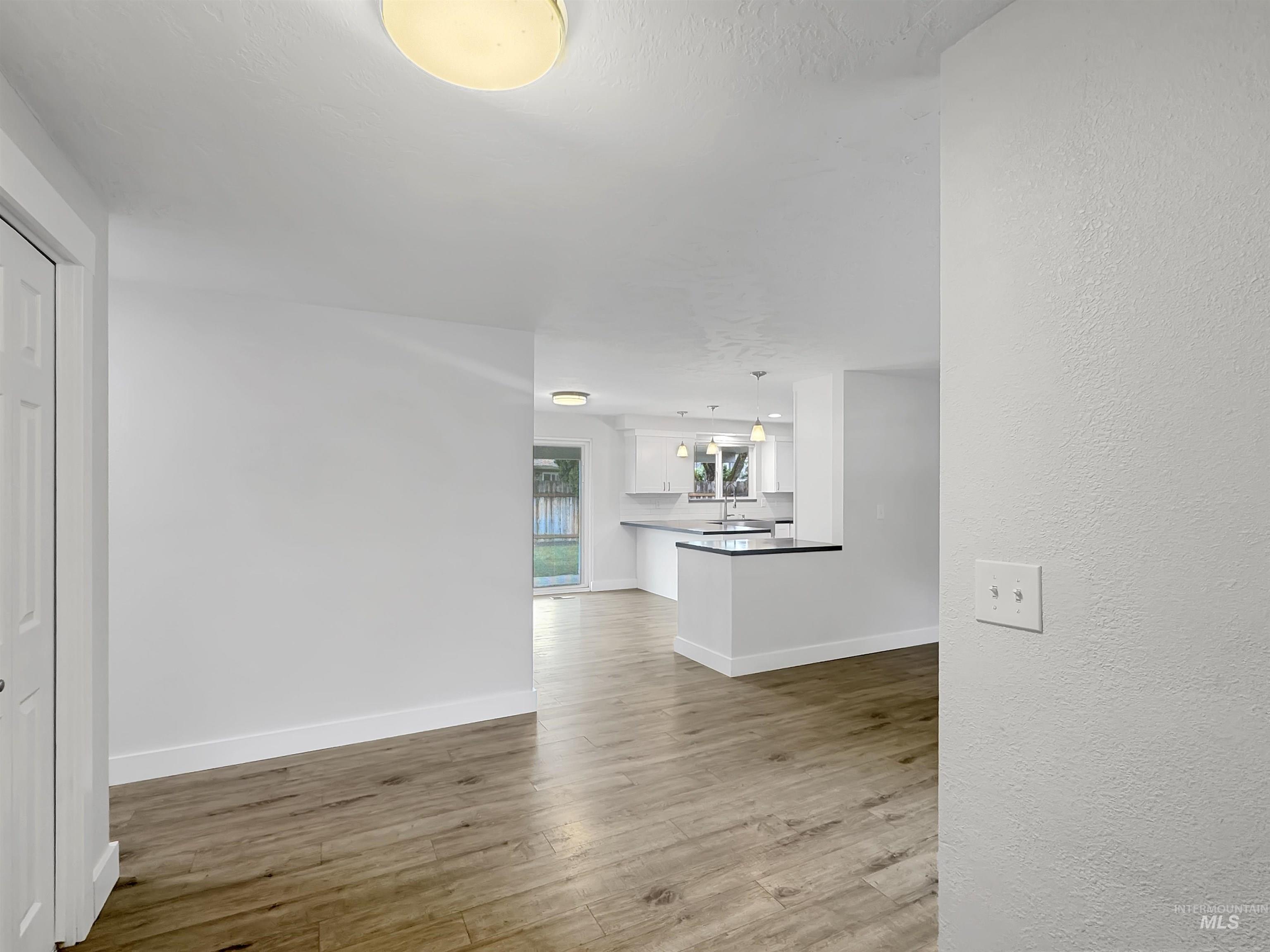 Open-concept interior featuring wood-finish flooring, white walls, and recessed lighting