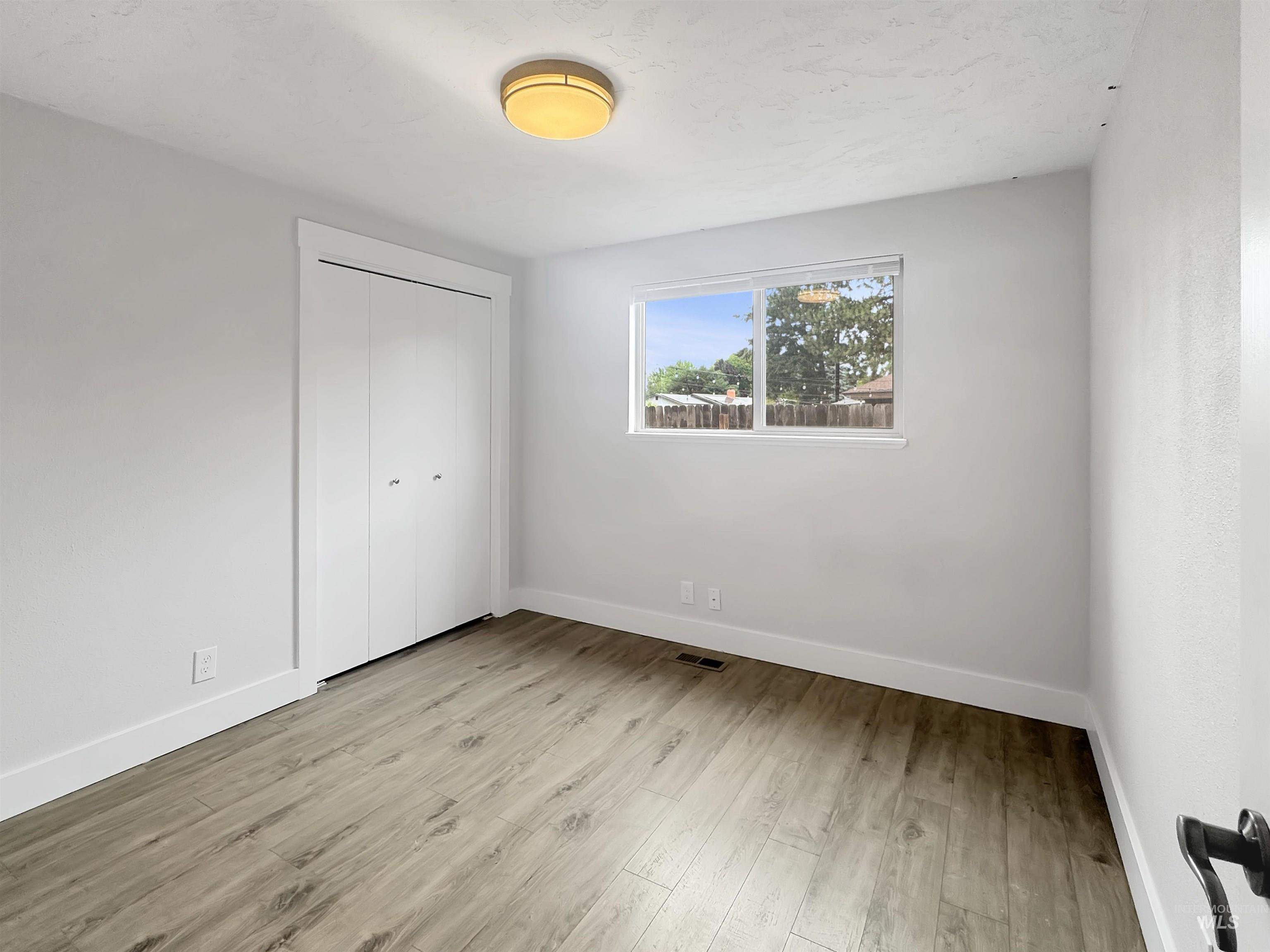 Room featuring wood-finish flooring, white baseboards, and light gray walls