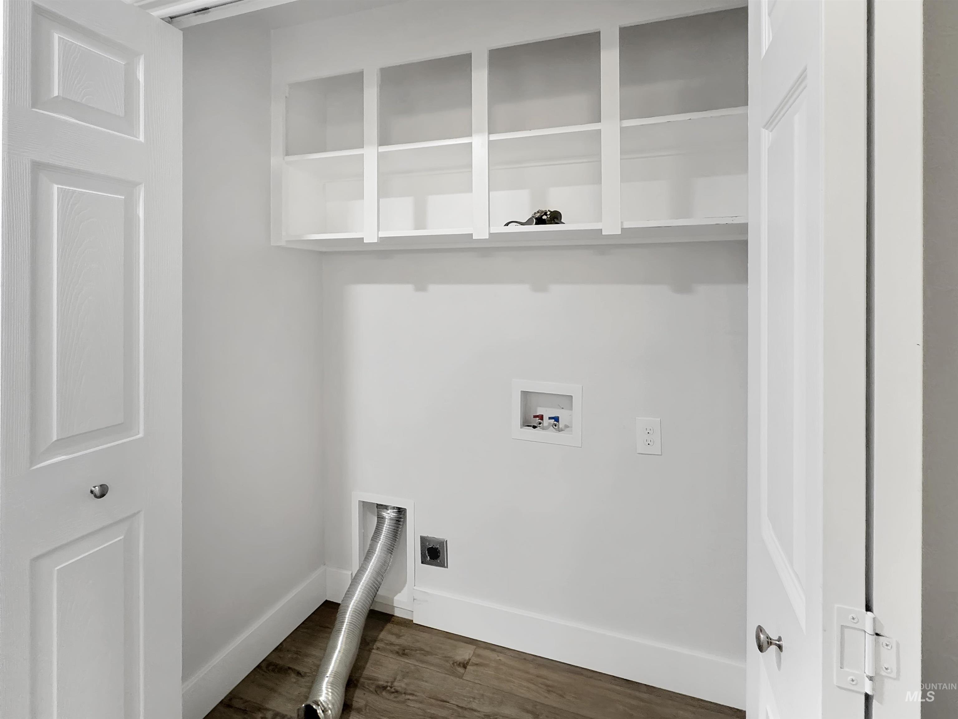 Dedicated laundry area featuring wood-finish flooring and white walls