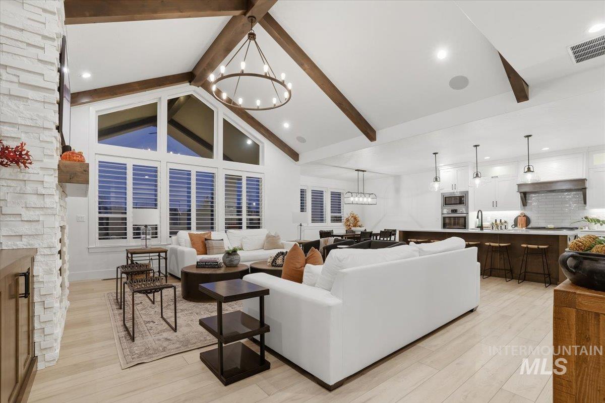 Living area featuring a chandelier, light wood-type flooring, high vaulted ceiling, beamed ceiling, and recessed lighting