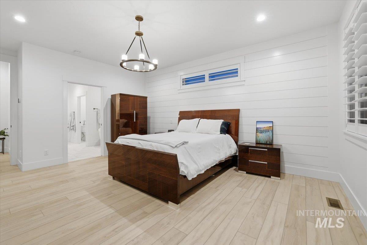 Bedroom featuring light wood-style flooring, wood walls, recessed lighting, and a chandelier