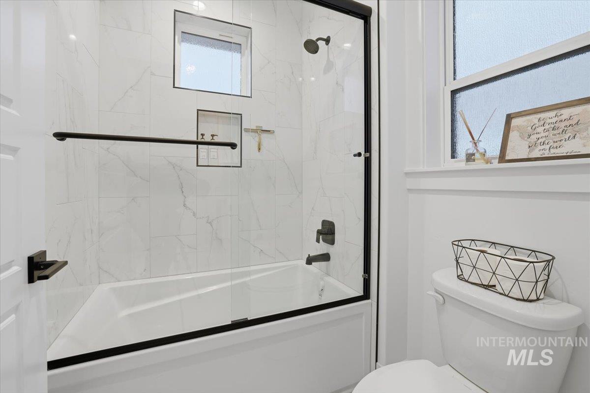 Full bathroom with combined bath / shower with glass door and toilet