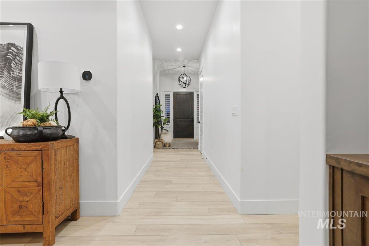 Hall featuring recessed lighting, light wood-style flooring, and a chandelier