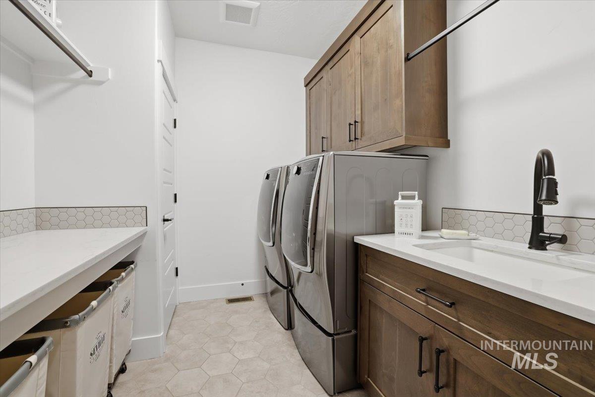 Laundry area featuring cabinet space, light tile patterned floors, and washing machine and clothes dryer