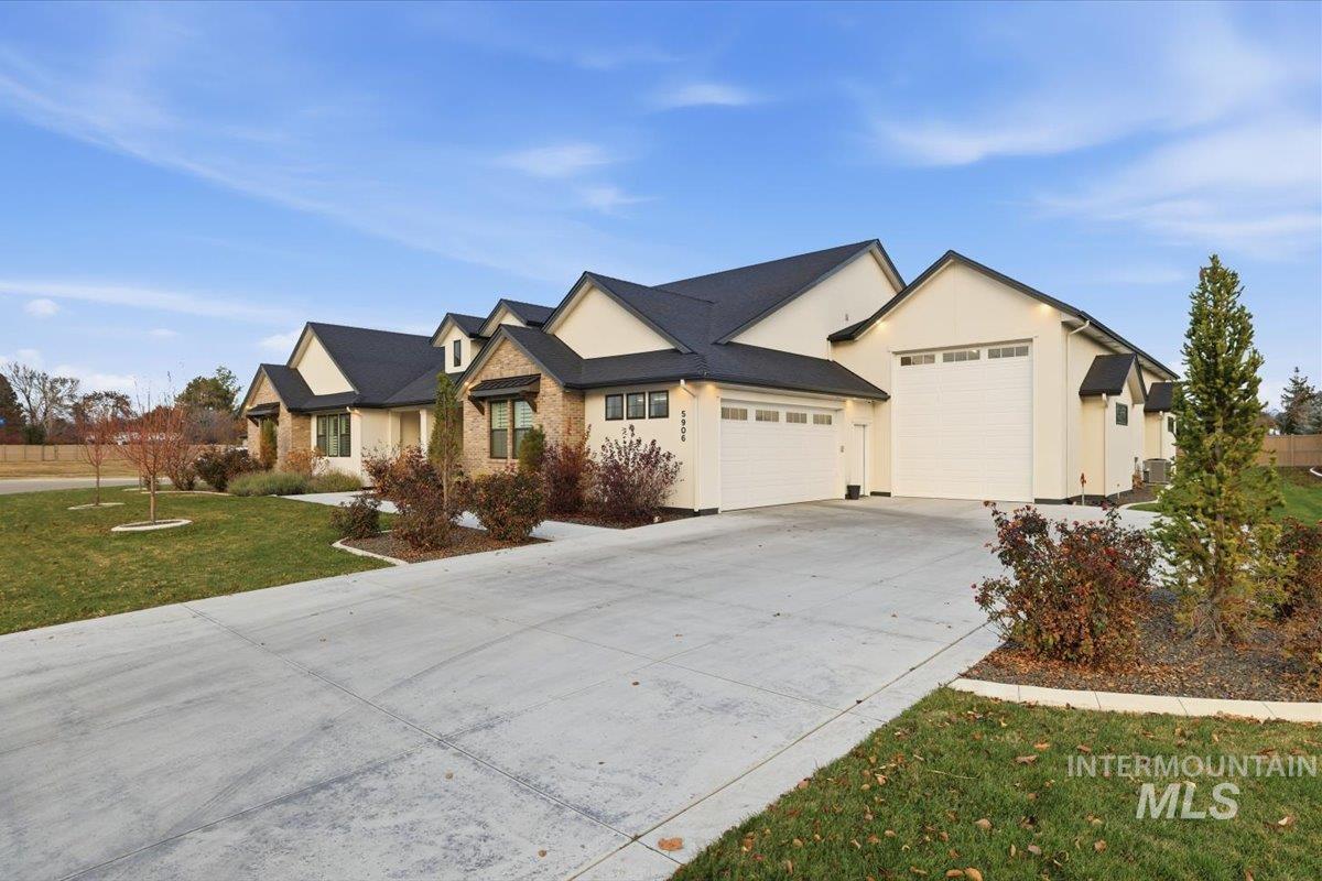 View of front of house with a front yard, concrete driveway, an attached garage, and stucco siding
