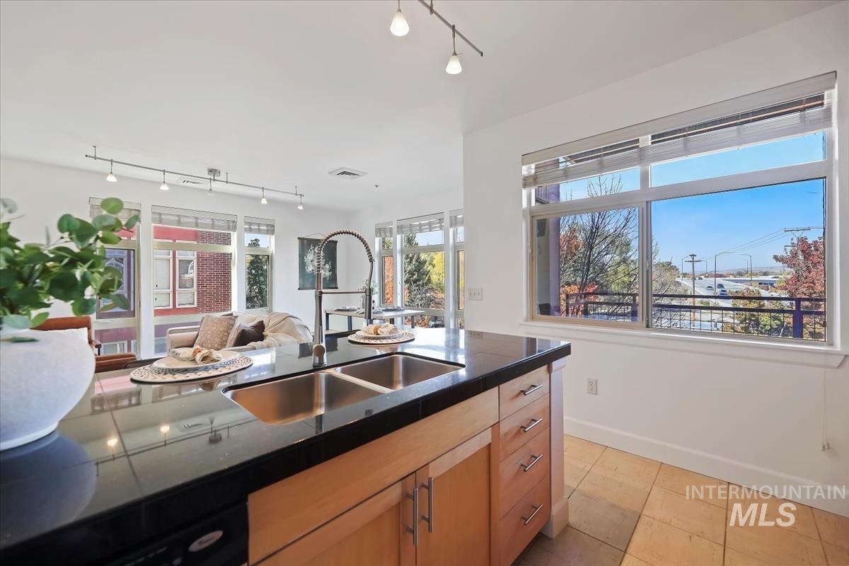 Kitchen with open floor plan, light tile patterned flooring, rail lighting, and light brown cabinets