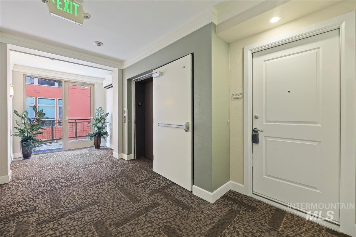 Corridor with dark carpet, elevator, and ornamental molding