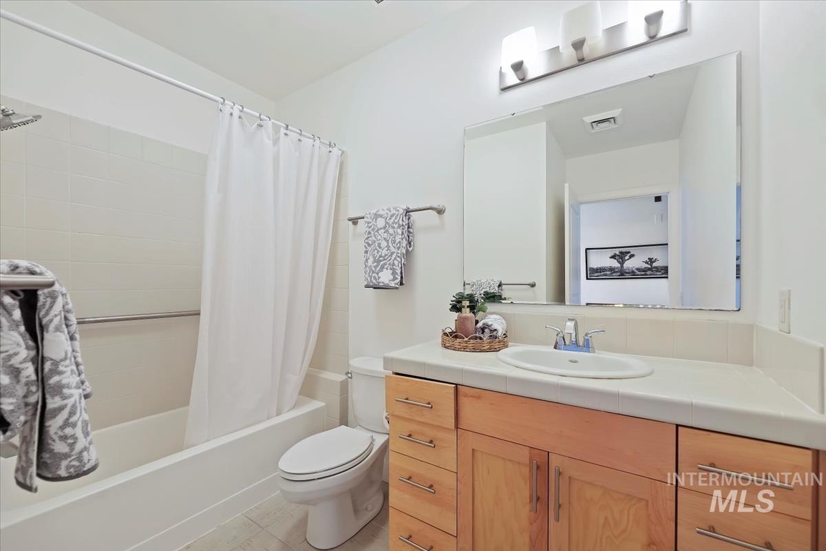 Full bathroom with shower / tub combo, vanity, and light tile patterned floors
