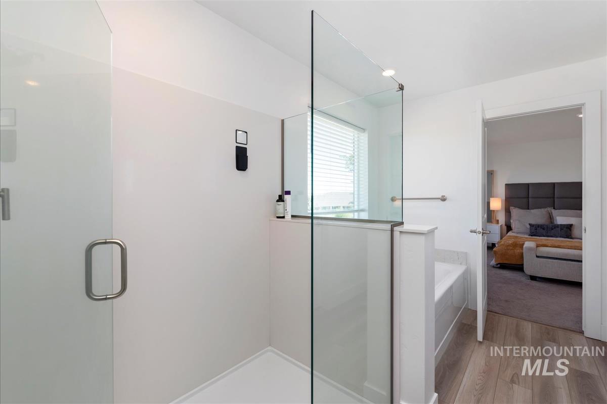 Glass-enclosed shower with contemporary hardware, featuring a half-wall partition