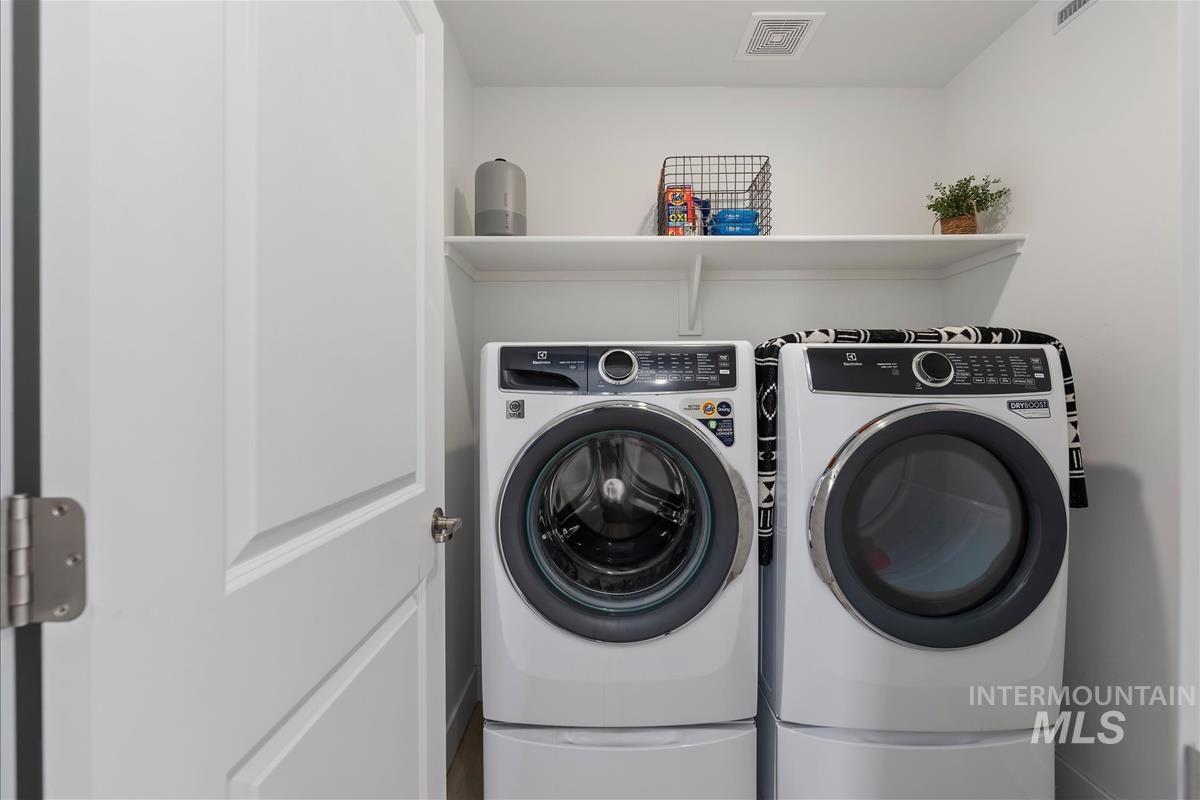 Dedicated laundry space featuring white paneled walls, a white overhead shelf, and recessed lighting