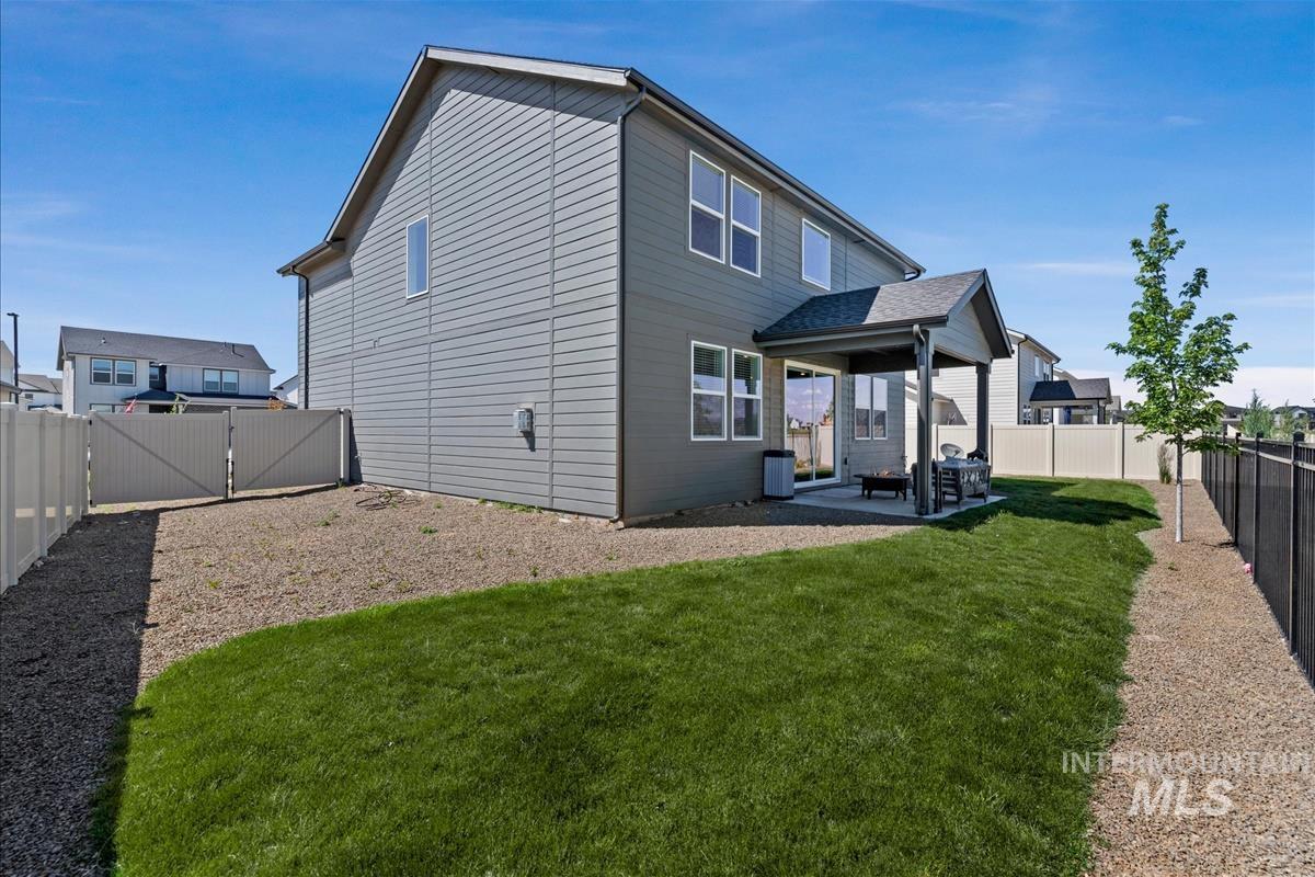 Expansive backyard featuring a covered patio, manicured lawn, and perimeter fencing