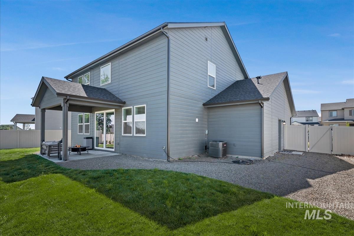 Rear elevation featuring a covered patio, sliding glass door, and a gravel and grass yard