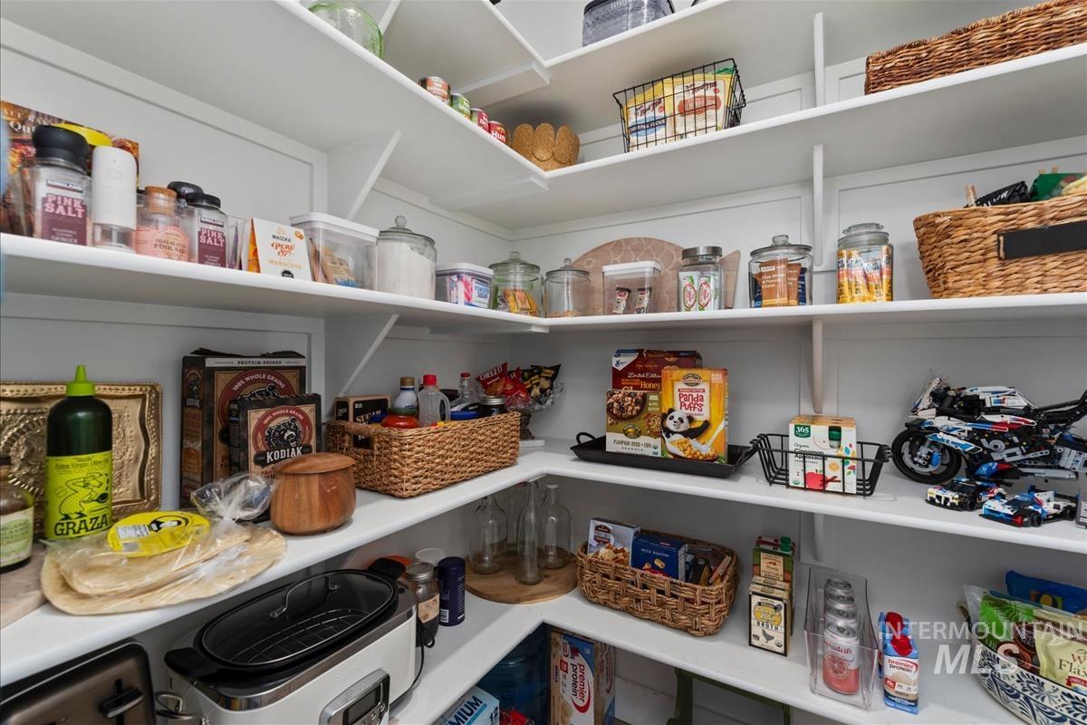 Expansive pantry featuring multi-level shelving, bright white finishes, and recessed lighting