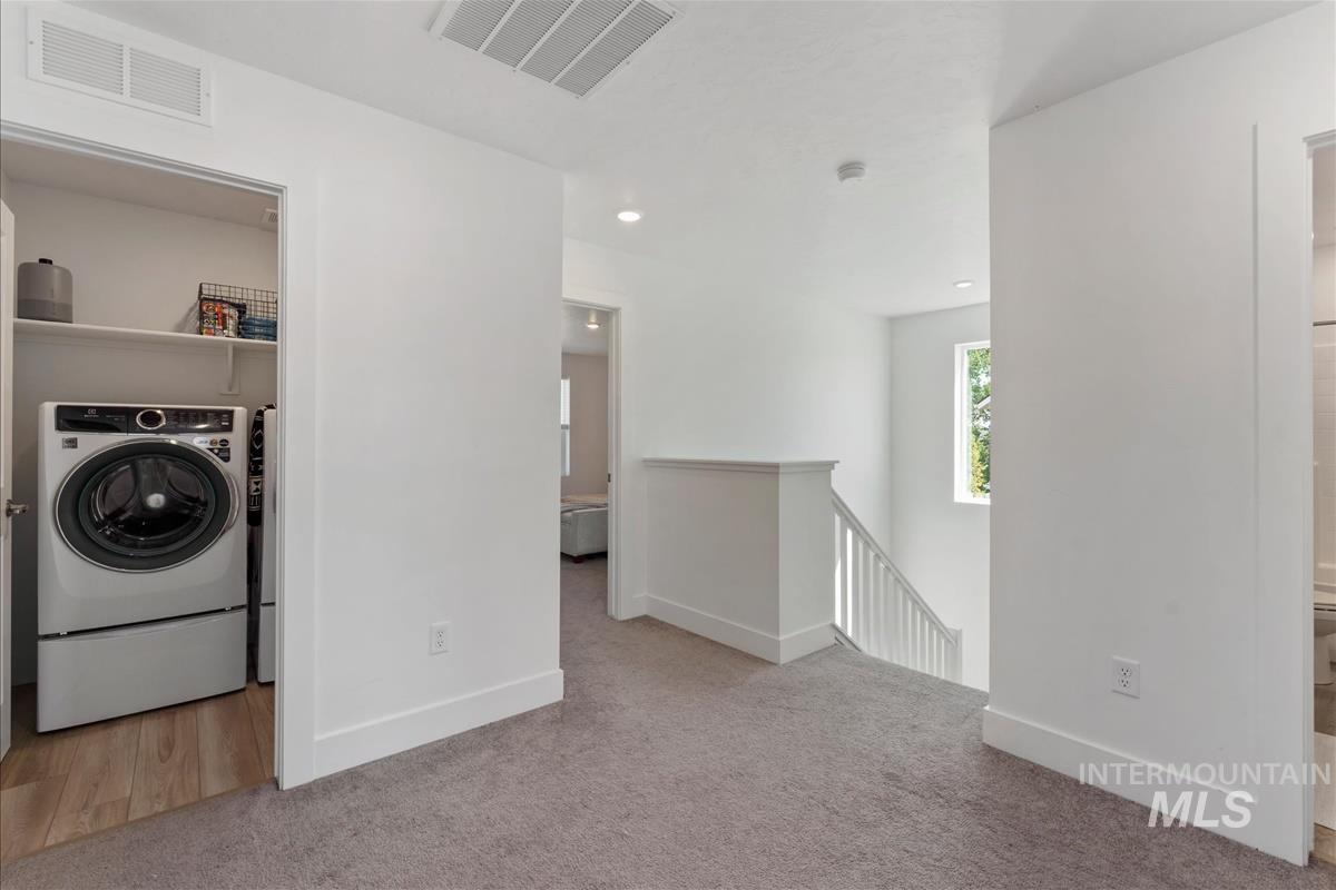 Upper-level landing featuring plush carpet, white walls, and a recessed lighting