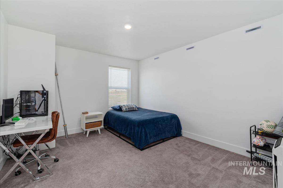 Spacious room featuring neutral carpeting, white walls, a recessed ceiling light, and a window with horizontal blinds
