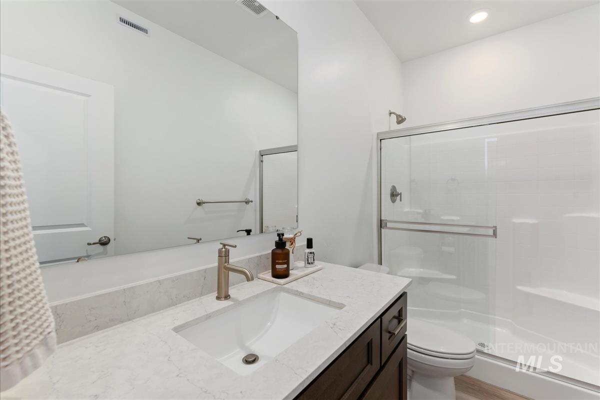 Contemporary bathroom featuring a spacious shower with sliding glass doors, a large vanity with an integrated sink, a substantial mirror, and recessed lighting