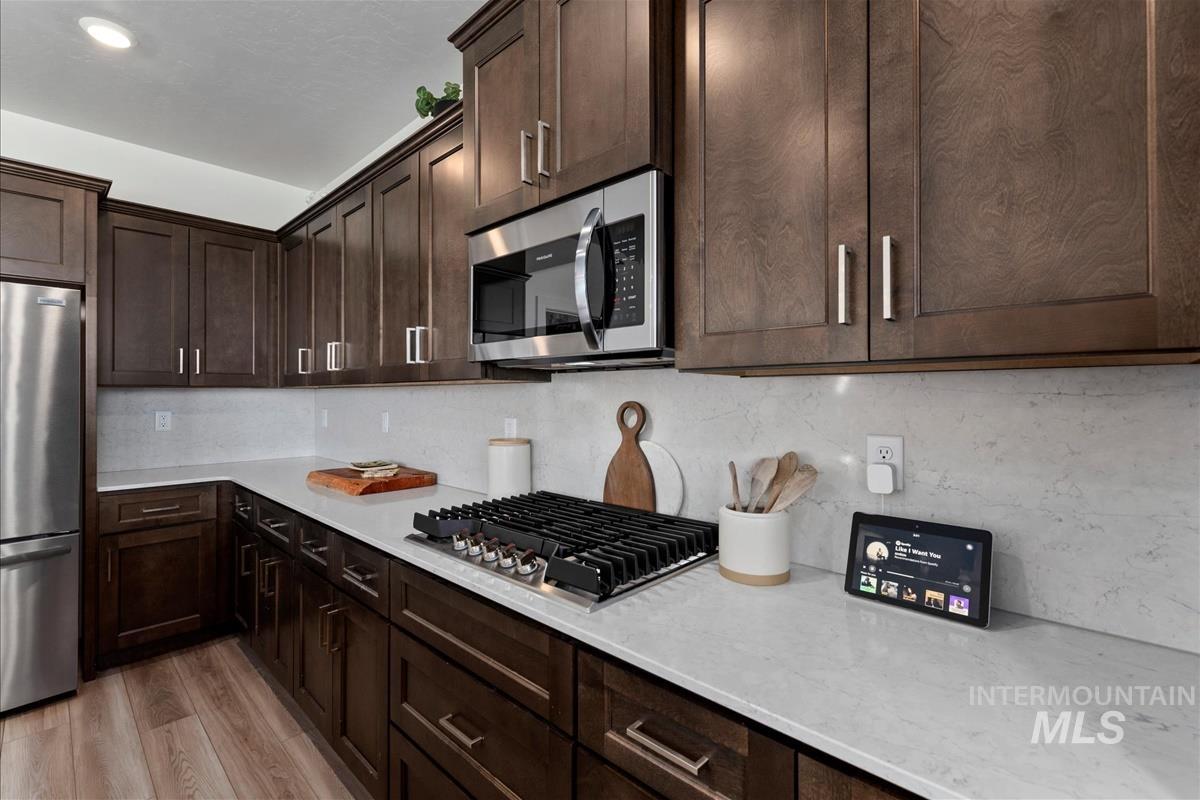 Kitchen featuring dark wood-finish cabinetry, light-toned countertops, and stainless steel appliances