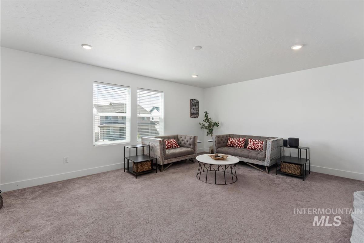 Spacious room featuring neutral carpet flooring, white painted walls, and recessed lighting