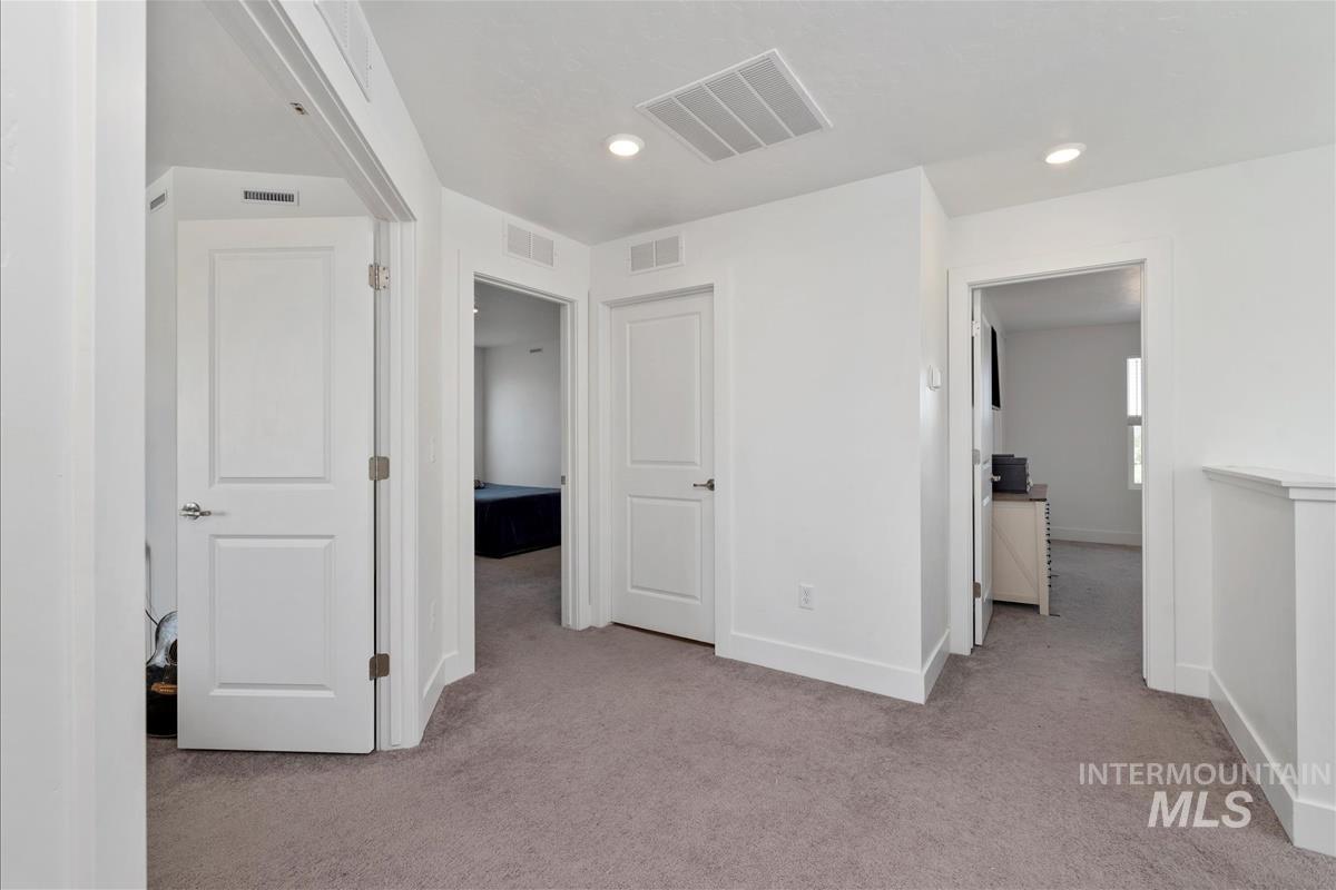 Central hallway featuring light-toned carpeting and white walls