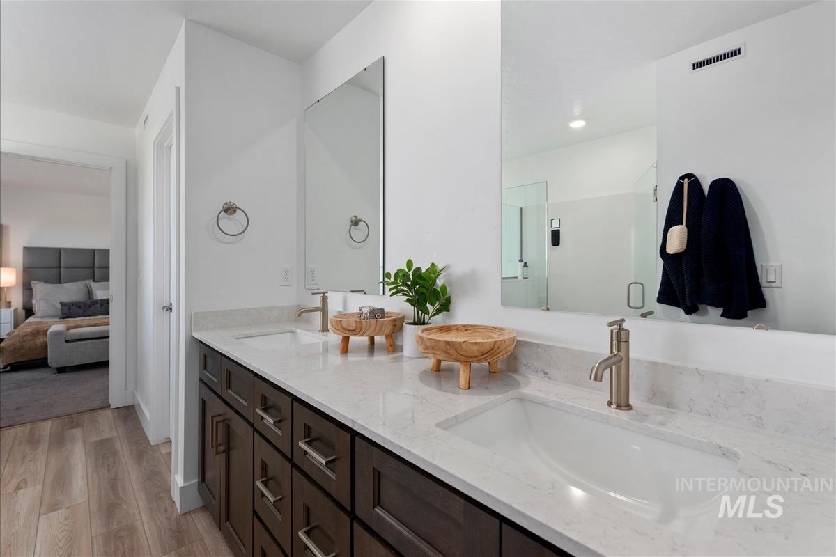 Double vanity featuring dark wood-finish cabinetry, white stone-finish countertops, and dual undermount sinks with brushed nickel single-handle faucets