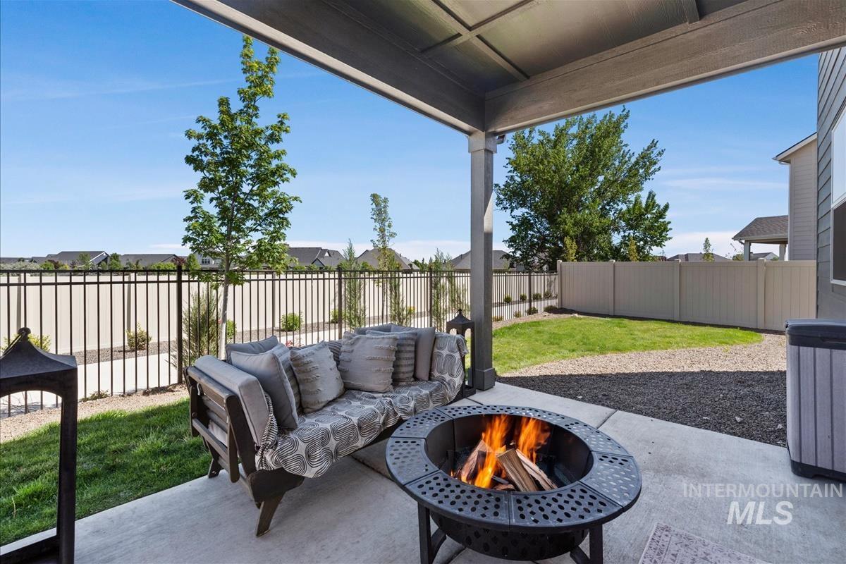 Covered patio space featuring a concrete slab, a built-in fire pit, and a dark gravel border