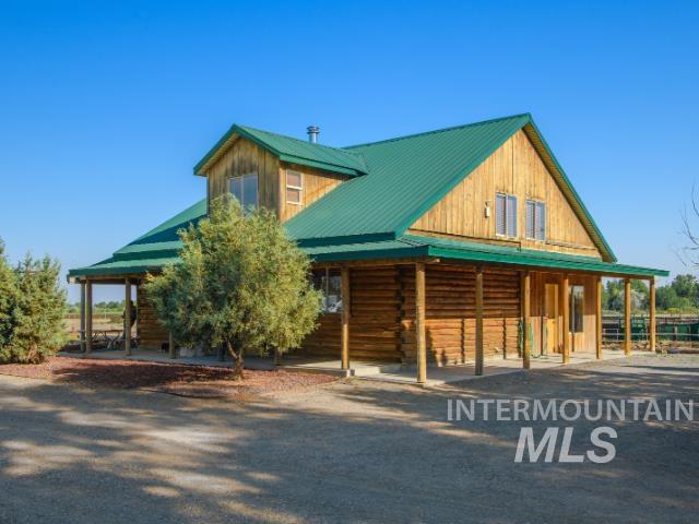 View of front facade with a metal roof, an exterior structure, covered porch, an outbuilding, and log siding