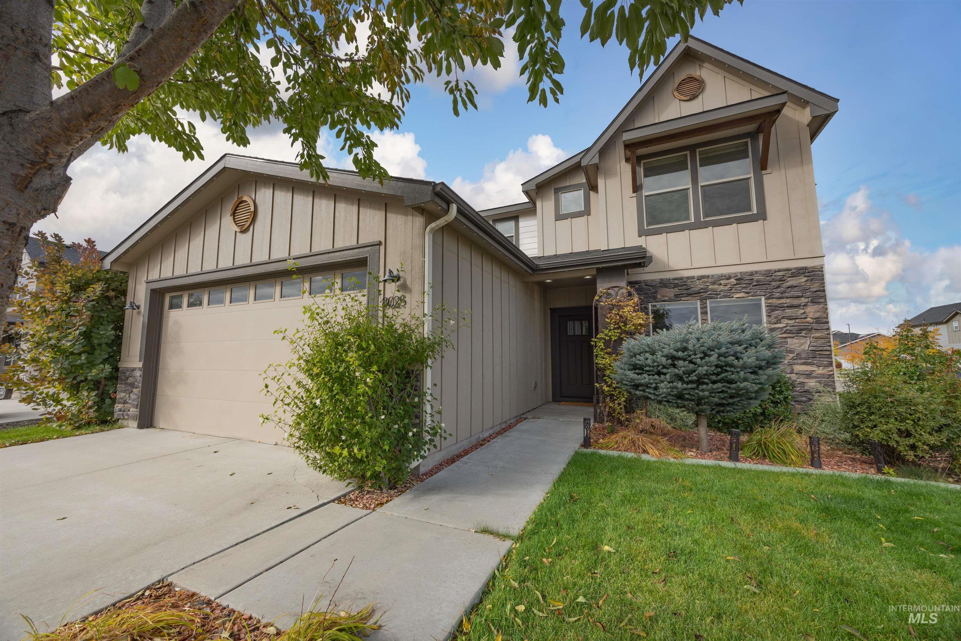 Craftsman house with board and batten siding, stone siding, an attached garage, and a front lawn