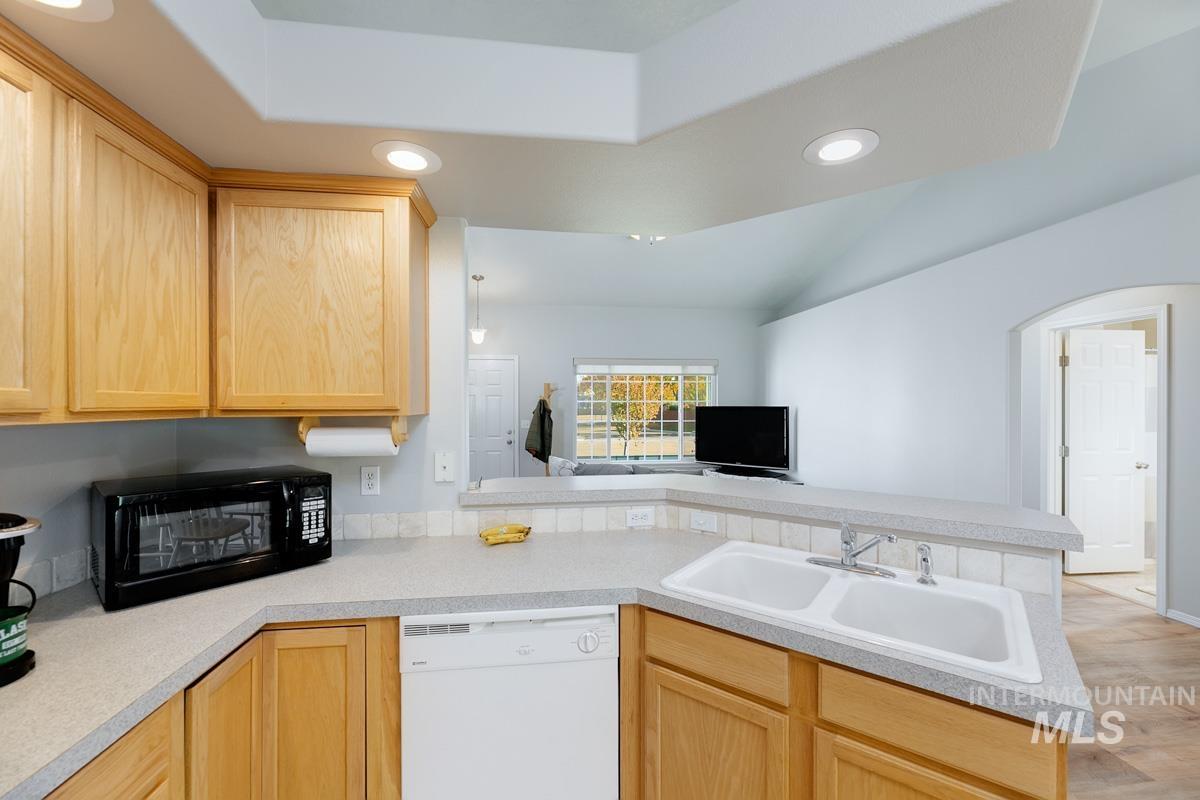 Kitchen featuring light brown cabinets, recessed lighting, dishwasher, light countertops, and a peninsula