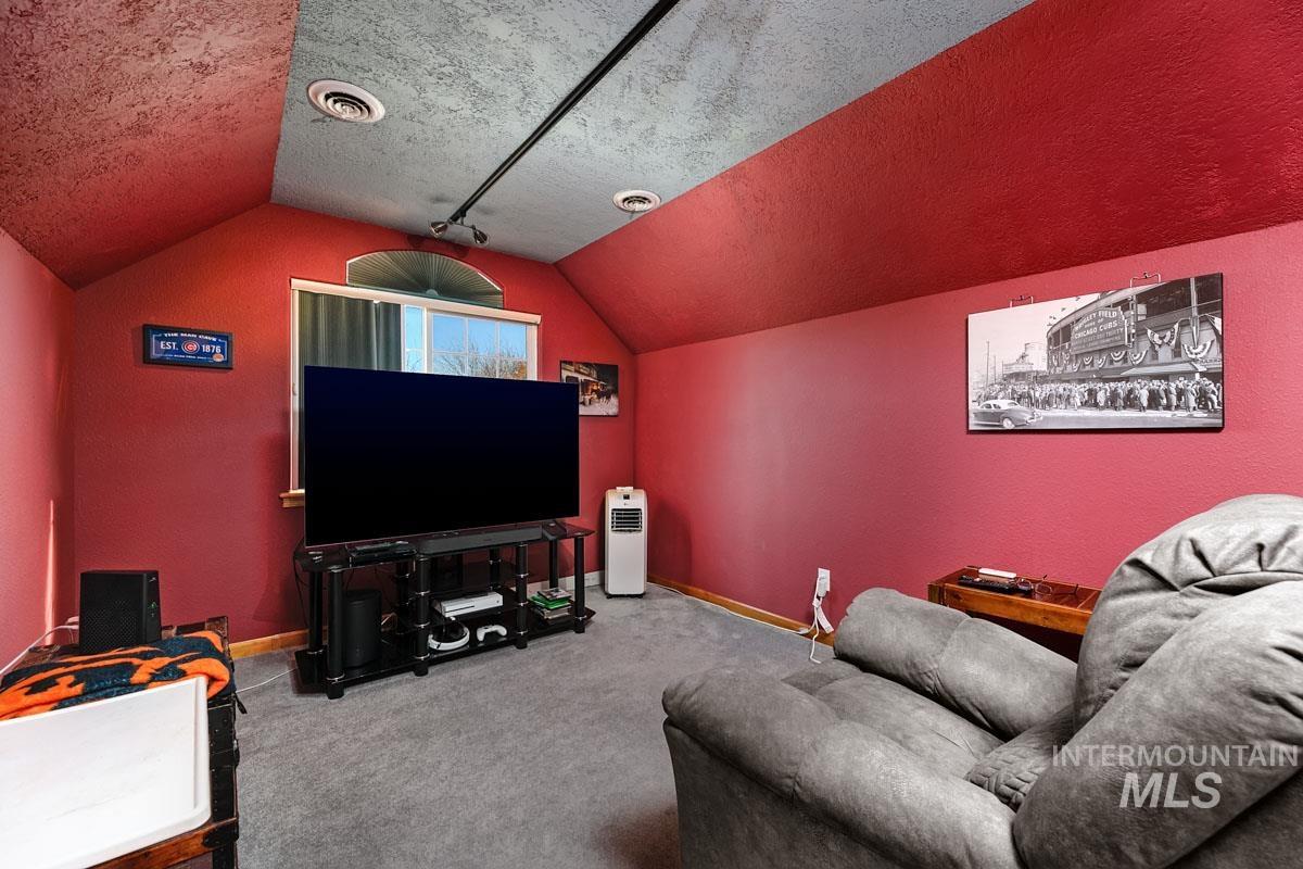 Living area featuring a textured ceiling, vaulted ceiling, carpet, and a textured wall