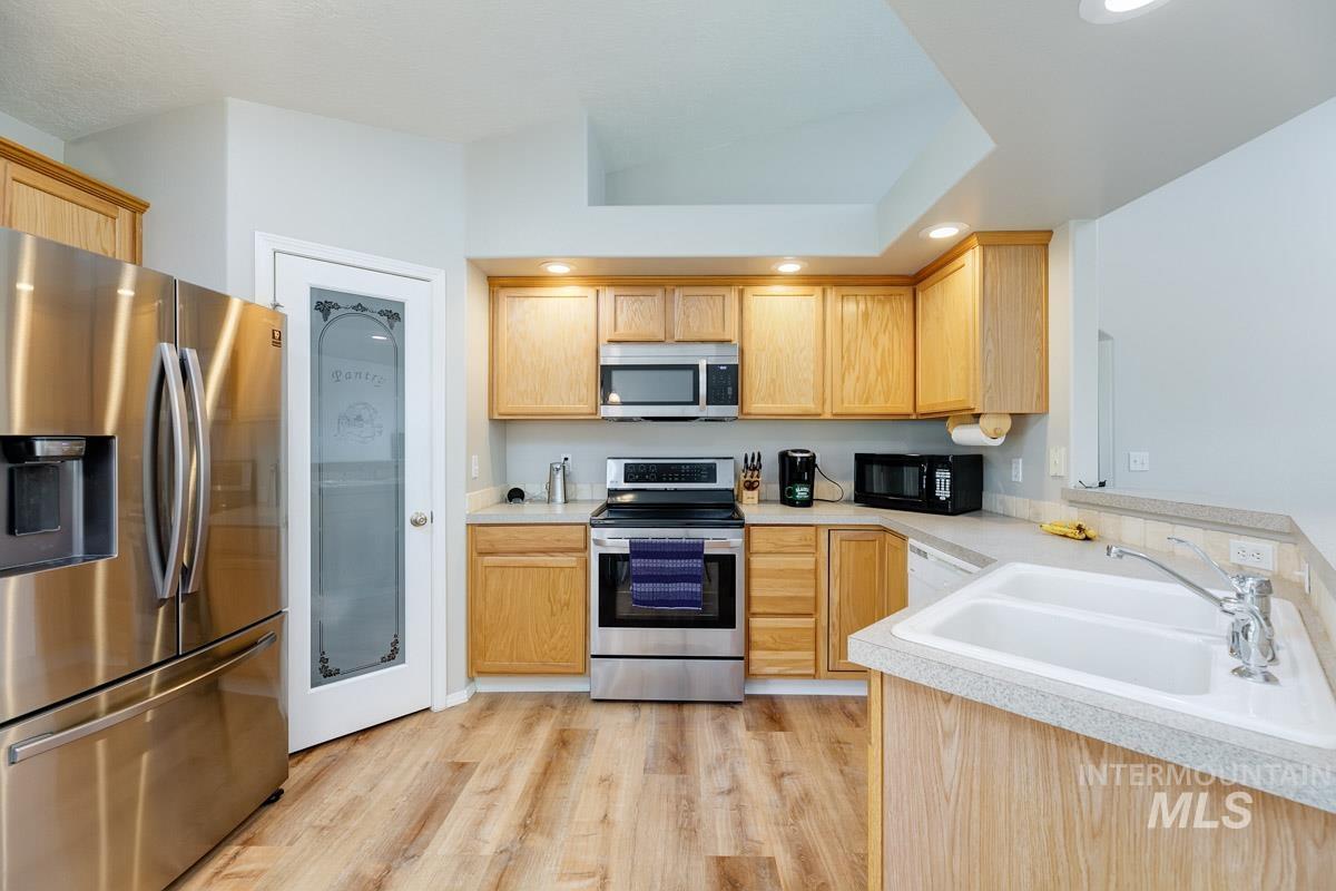 Kitchen with stainless steel appliances, light wood-style floors, light countertops, recessed lighting, and light brown cabinets