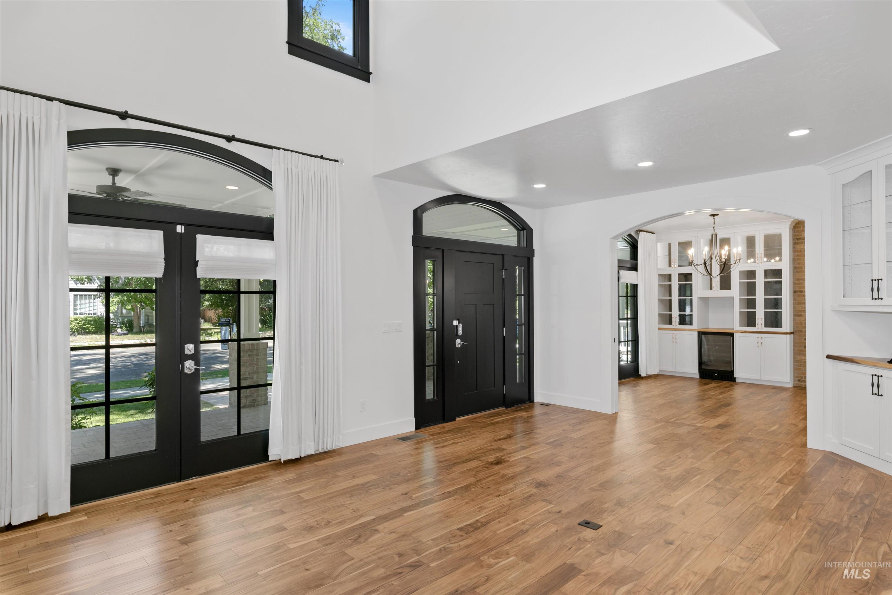 Entryway featuring light wood finished floors, arched walkways, a chandelier, recessed lighting, and wine cooler